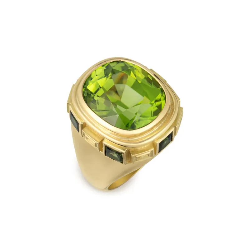 <p>Elizabeth Gage Charlemagne ring with a cushion-shaped faceted peridot of 15.44 carats, surrounded by six square princess-cut green tourmalines totalling 1.61 carats in 18k yellow gold</p>