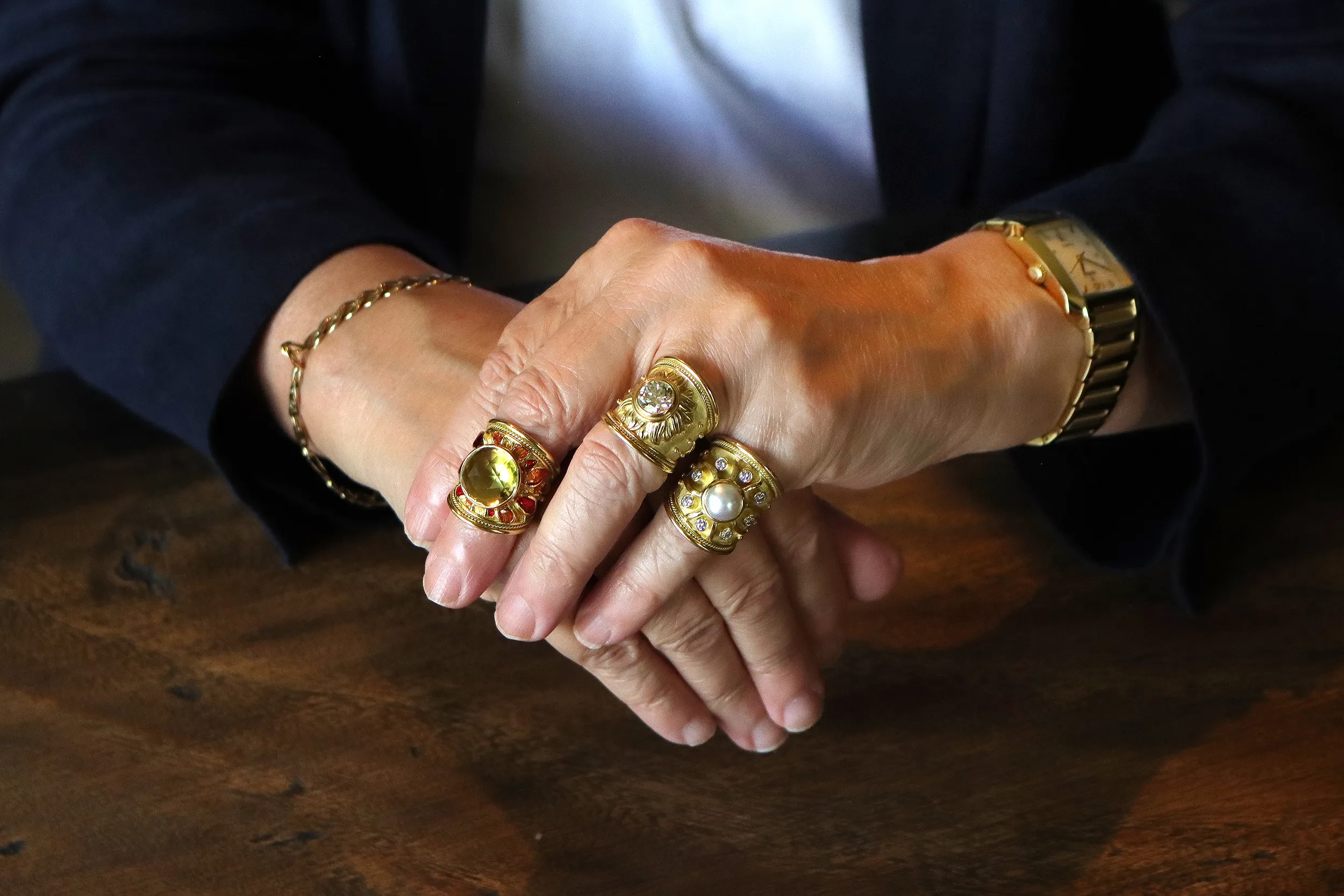 <p>Joanne Rees wears a trio of rings by Elizabeth Gage including the Sun ring with a 2.98 carat old-cut diamond and the Sun ring with a round mabé pearl and brilliant-cut diamond (right), all in 18k yellow gold</p>