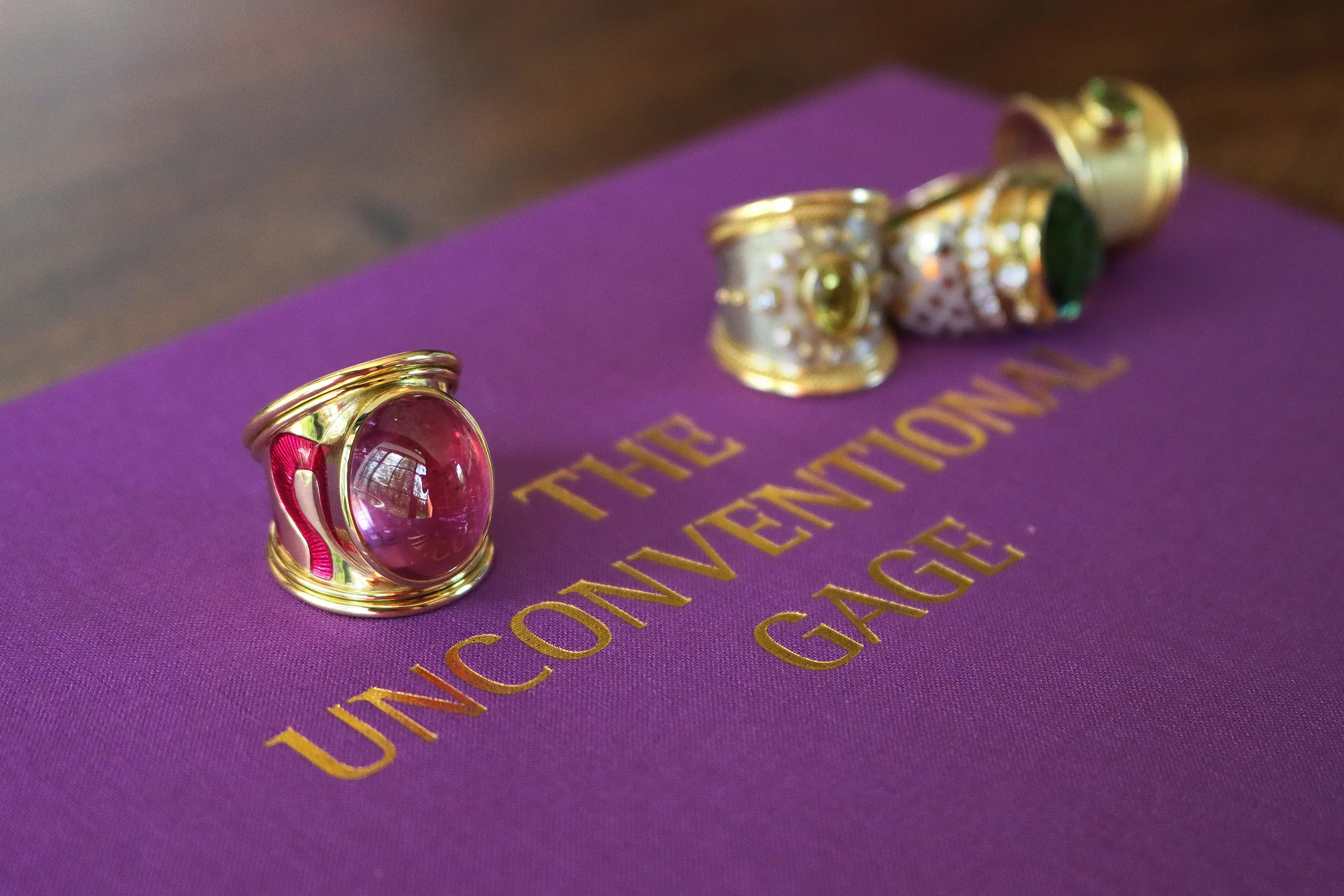 <p>A closer look at signature rings by Elizabeth Gage, including an enamel wave tapered Templar ring with a 17.56 carat fuchsia-coloured pink tourmaline cabochon set in 18k yellow gold</p>