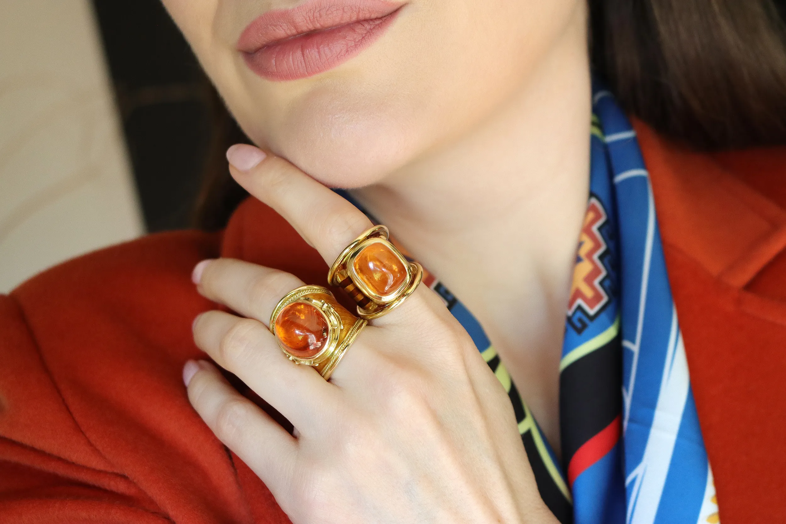 <p>Katerina Perez wears the Elizabeth Gage tapered Templar ring (left) with a 29.37 carat oval-shaped mandarin garnet cabochon, brilliant-cut diamonds and saffron enamel alongside the Aramis ring with a cushion-shaped sugarloaf cabochon mandarin garnet of 15.80 carats, accented with brown and orange enamel, both in 18k yellow gold</p>
