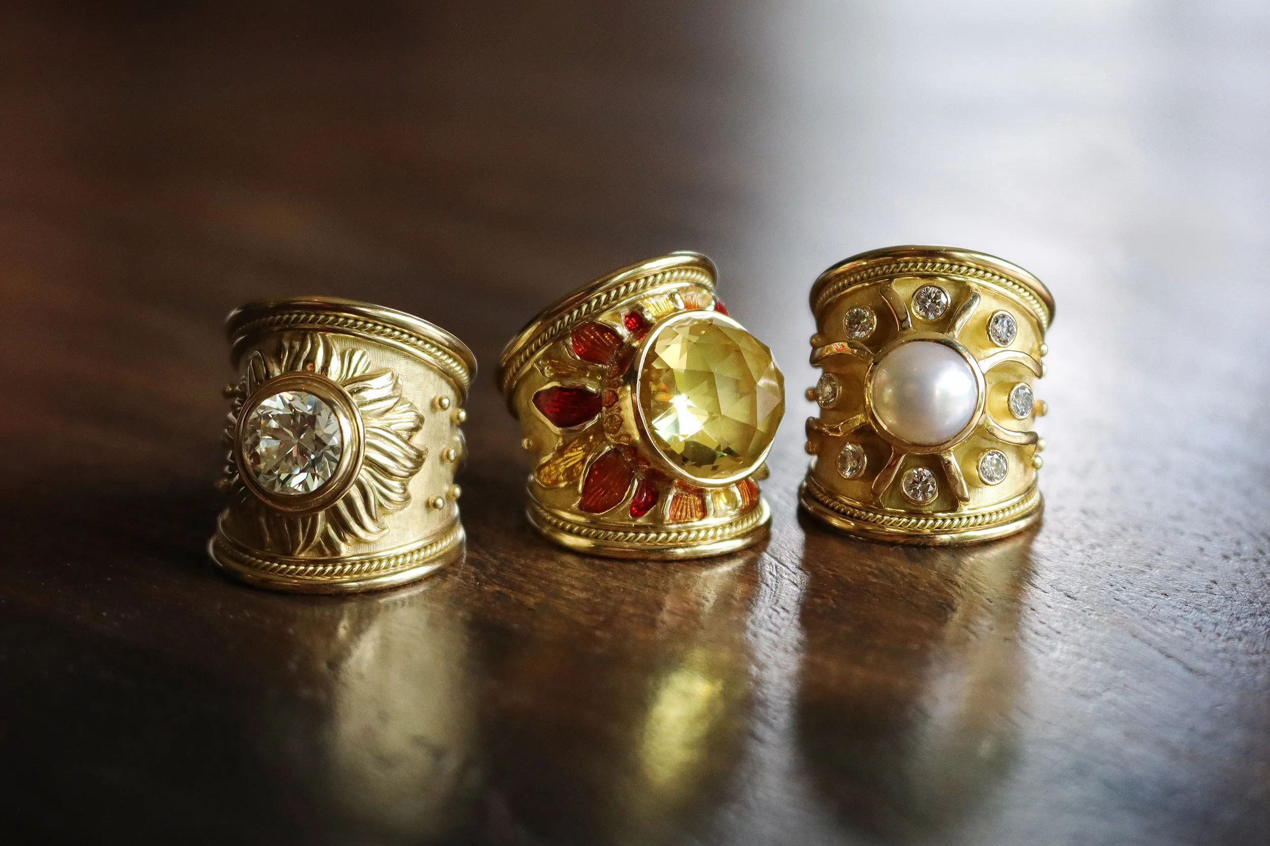 <p>A trio of rings by Elizabeth Gage including the Sun ring with a 2.98 carat old-cut diamond (left) and the Sun ring with a round mabé pearl and brilliant-cut diamond (right), all in sculpted 18k yellow gold</p>