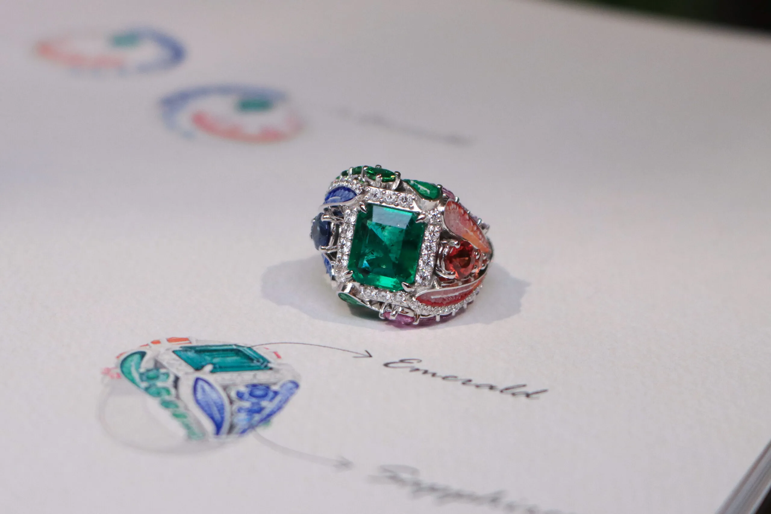 <p>SICIS Colibrì ring with a rectangular step-cut emerald, further emeralds, diamonds, sapphires and malachite with colourful micromosaic ‘feathers’, set in white gold</p>