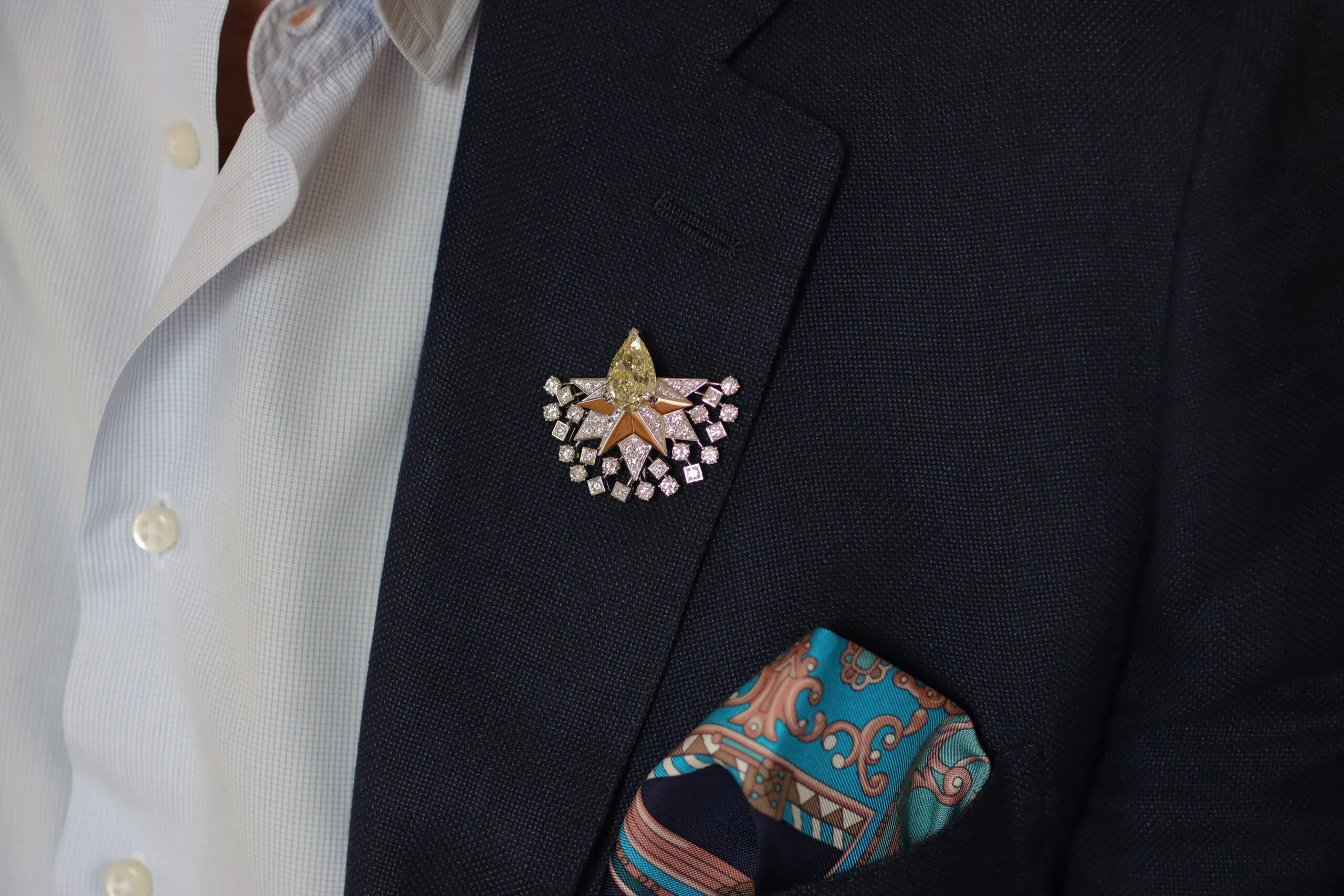 <p>Sahag Arslanian wears the central motif of the Sun Rays High Jewellery necklace as a lapel brooch, set with an 8.88-carat pear-shaped fancy yellow VS2 diamond and surrounded by white diamonds in 18k white and yellow gold </p>
