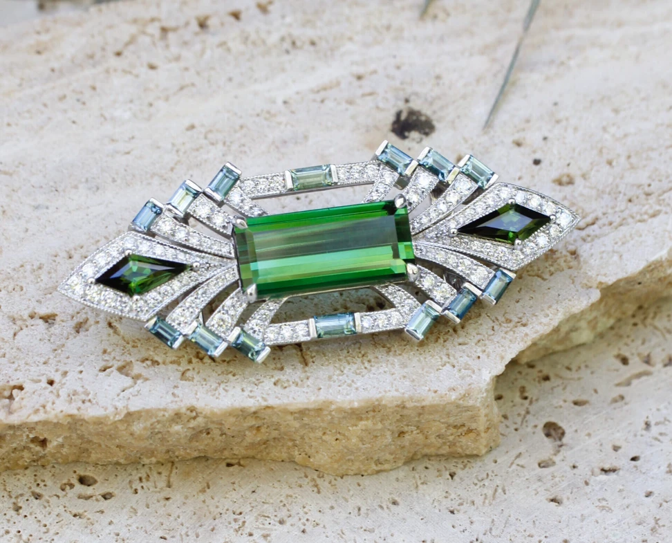 <p>Nicole Winkler transformable brooch-pendant with a vivid green tourmaline, pavé-set diamond arcs, green sapphire baguettes, and kite-shaped tourmalines</p>
