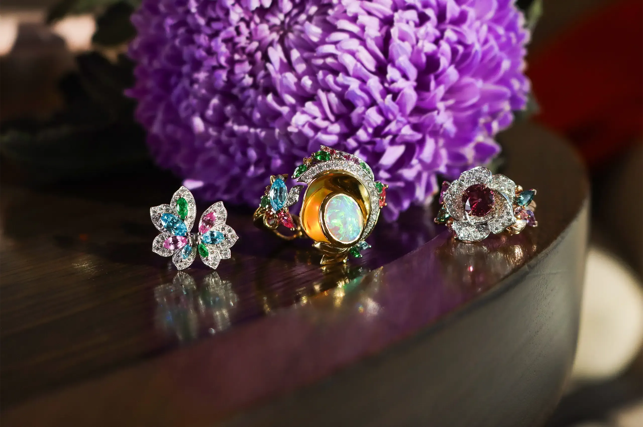 Artisans Bespoke Jewellers rings, including (from left to right) the Angelique ring with blue zircon, tsavorite garnet, pink sapphire and diamonds in 18k white gold; the Khroma ring with a 3.45 carat crystal opal cabochon and zircon, sapphire, garnet, spinel and diamonds in 18k yellow and white gold, and the Botanica Lady Beetle ‘Rose’ ring with a 1.79 carat pink-purple sapphire surrounded by diamonds, and green, purple and pink sapphire leaves, set in 18k rose and white gold