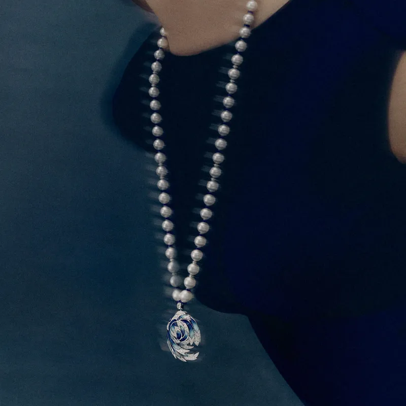 <p>The winged Envol high jewellery pendant, worn on a sapphire-and-pearl sautoir, swivels open to reveal a sodalite watch face</p>
