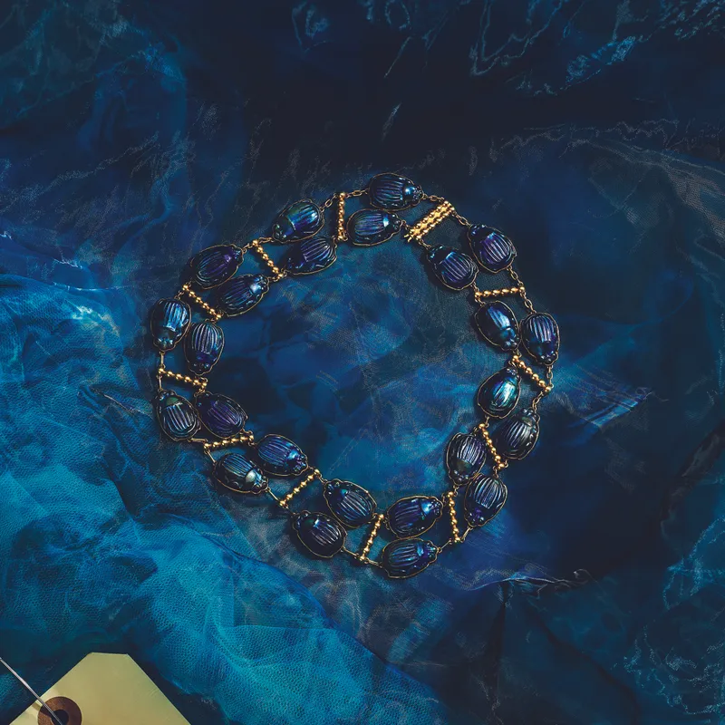 <p>The Favrile Glass Scarab necklace from the early 1900s, designed by Louis Comfort Tiffany and worn by Mia Goth as Elizabeth Lavenza, features two rows of iridescent glass beetle motifs</p>