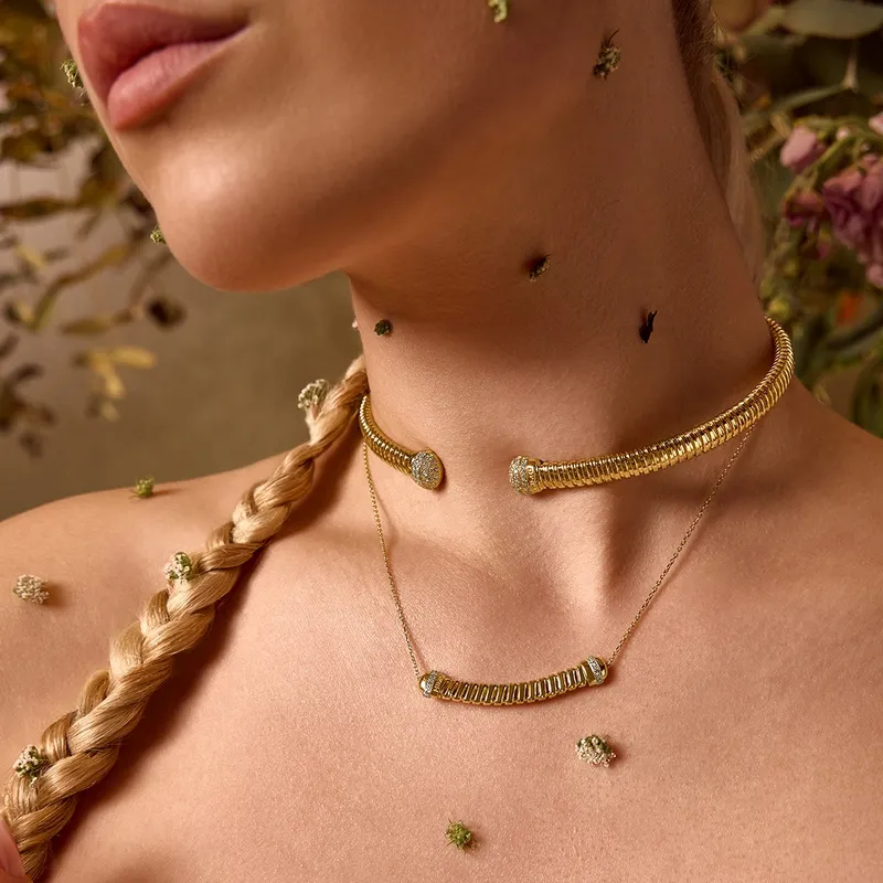 <p>Inspired by a more natural aesthetic, a model wears the Tourbillon collection choker and a more delicate necklace, both in 18k yellow gold with diamond accents</p>