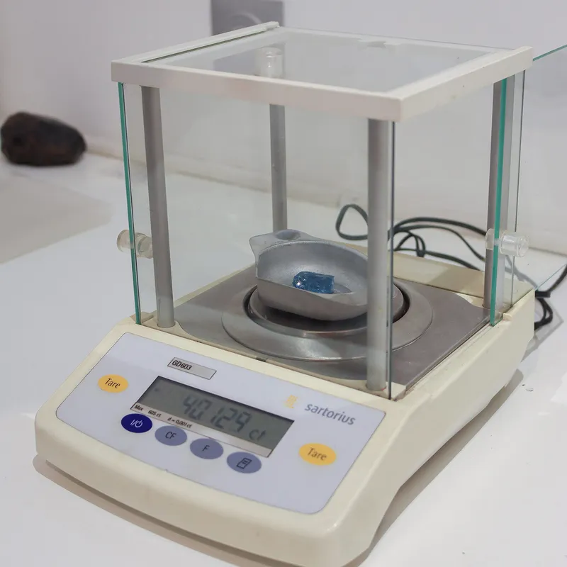 <p>The careful process of weighing gemstone rough, in this case a large blue sapphire crystal, before deciding how best to cut the stone for maximum size, saturation and clarity</p>
