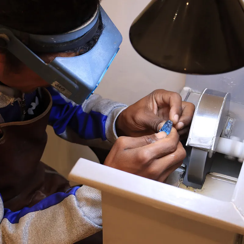 <p>A member of the Morebelli team begins the cutting process for a large piece of blue sapphire rough material</p>