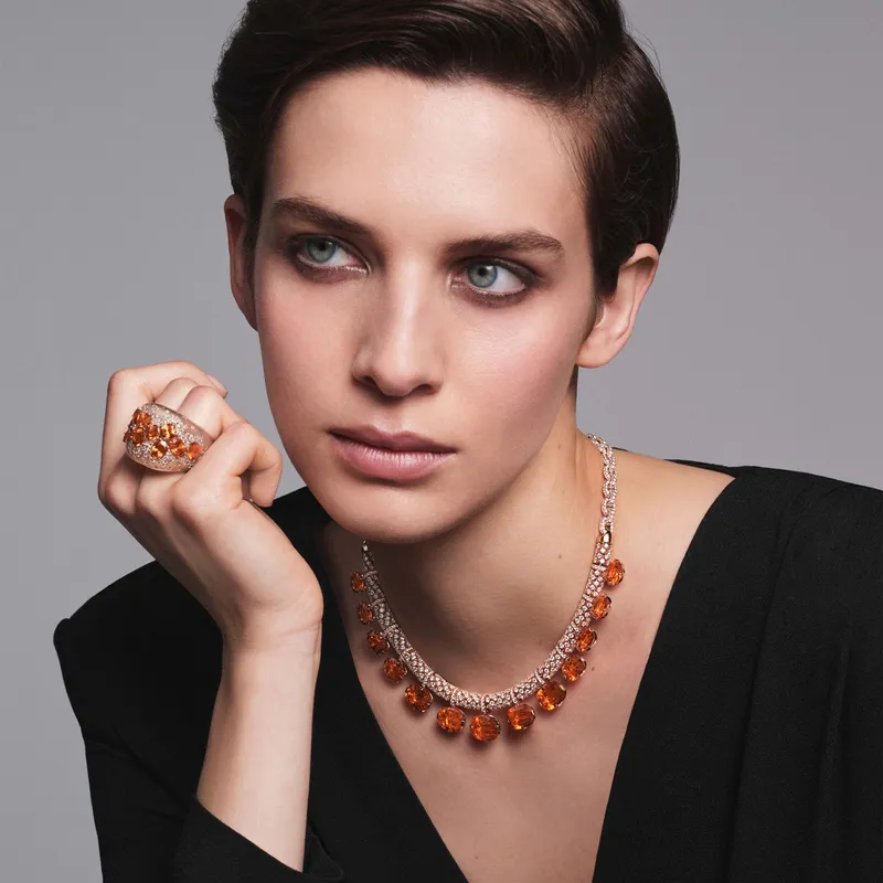 A model wears Pomellato Stile Libero Mandarine Mirage necklace in rose gold with 13 cushion-cut Mandarin garnets and 2,358 diamonds and Serti Libre ring in rose gold with 11 fancy-cut Mandarin garnets, 217 brown diamonds