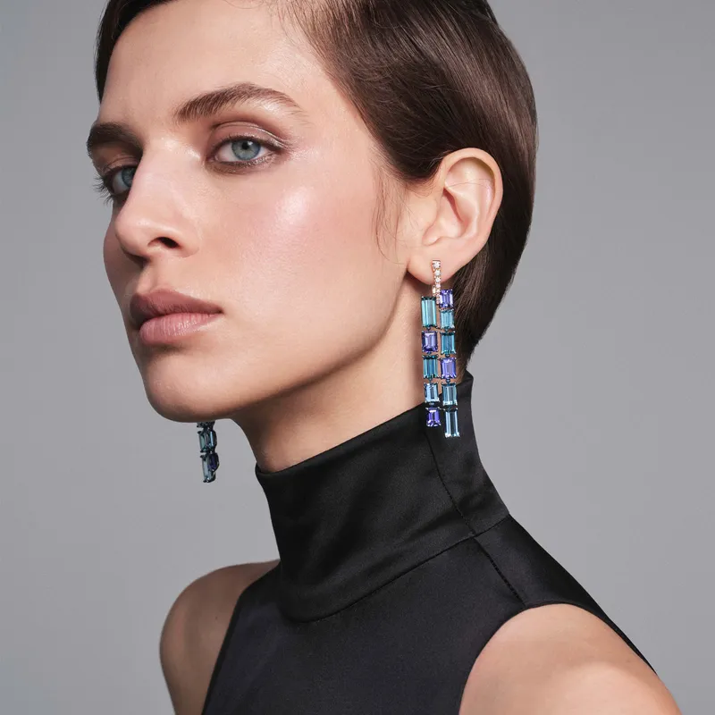A model wears Pomellato Stile Libero Mosaic Cascade earrings in rose gold and blue titanium with 8 rectangular-cut tanzanites, 8 rectangular-cut zircons, 6 rectangular-cut aquamarines and 16 diamonds