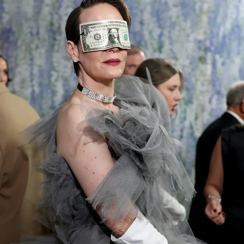 <p>Sarah Paulson arrived in an exaggerated tulle gown by Matières Fécales, worn with a Ruban Diamants choker by Boucheron and an oversize dollar bill obscuring her eyes</p>
