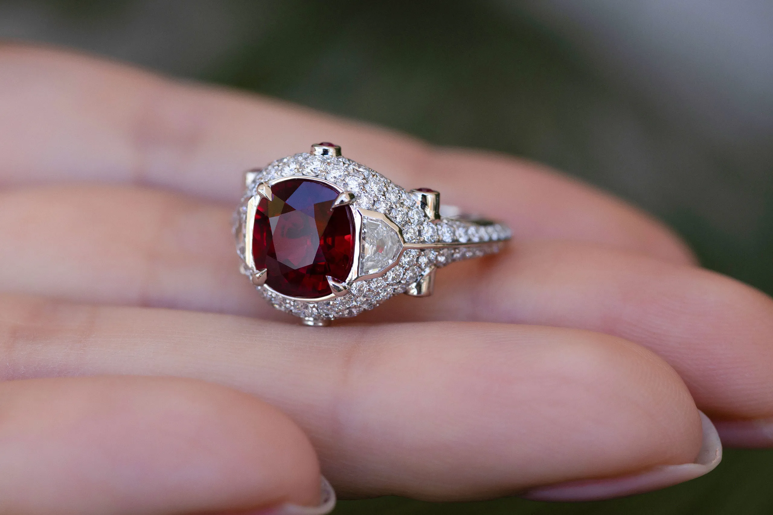 Two epaulette diamonds flank the centre stone, their reflective facets intensifying the ruby’s deep red colour