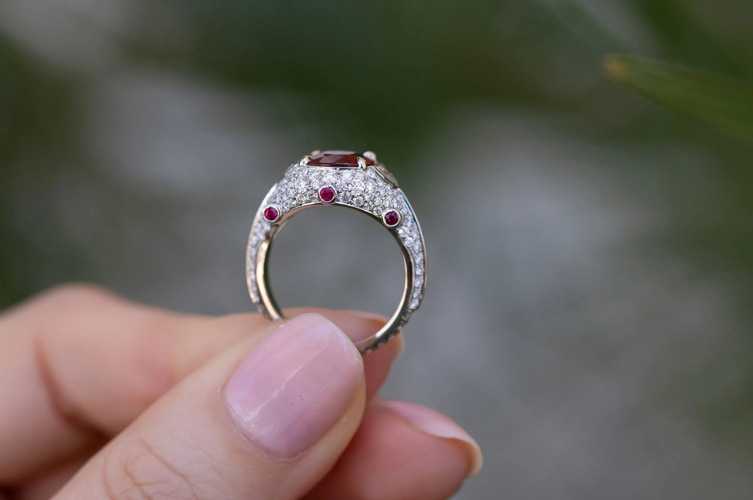 Viewed in profile, the ring reveals bezel-set rubies tucked among the diamond pavé