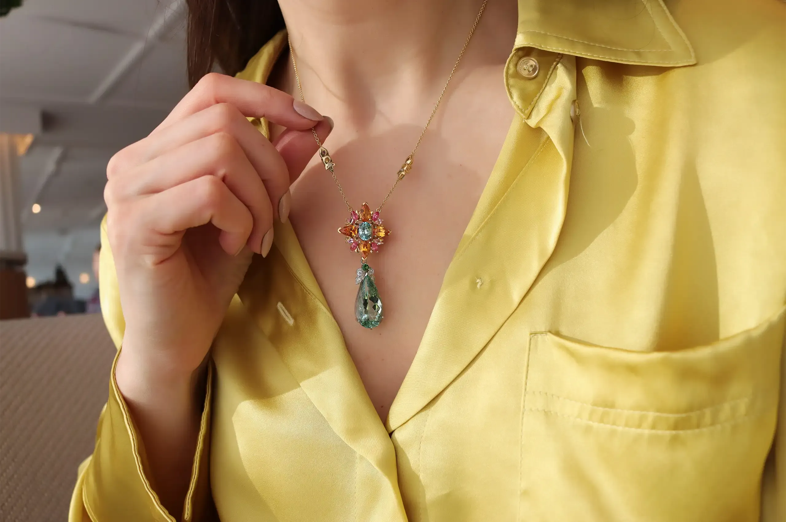 Katerina Perez wears the Artisans Bespoke Jewellers Botanica pendant with sapphire, garnet, spinel, zircon, diamond and a detachable aquamarine, zircon and diamond drop, set in 18k yellow and white gold 