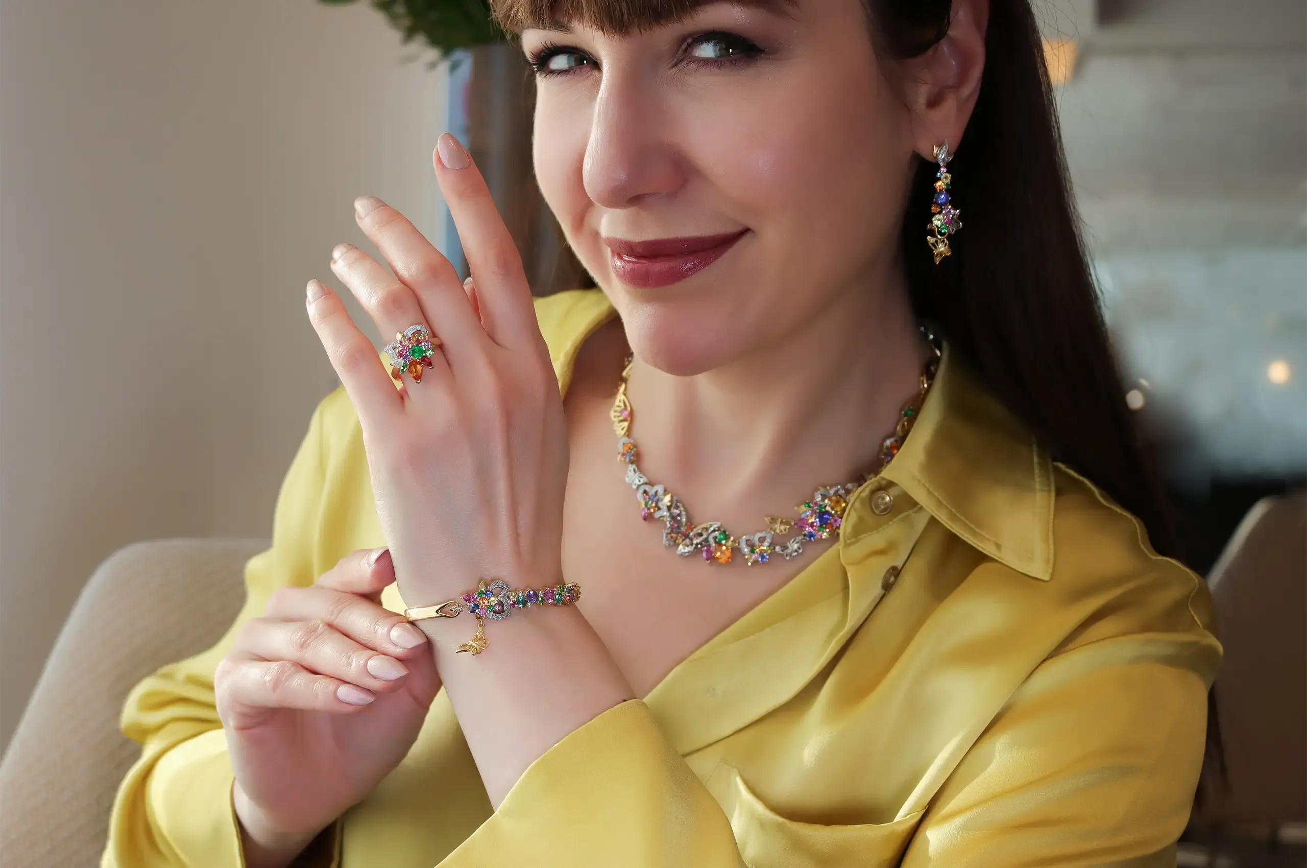 Katerina Perez wears the Borboleta suite of jewels by Artisans Bespoke Jewellers, including a necklace, a ring, a bracelet and a pair of earrings set with tanzanite, spinel, tsavorite garnet, mandarin garnet, sapphires and diamonds in 18k yellow and white gold 