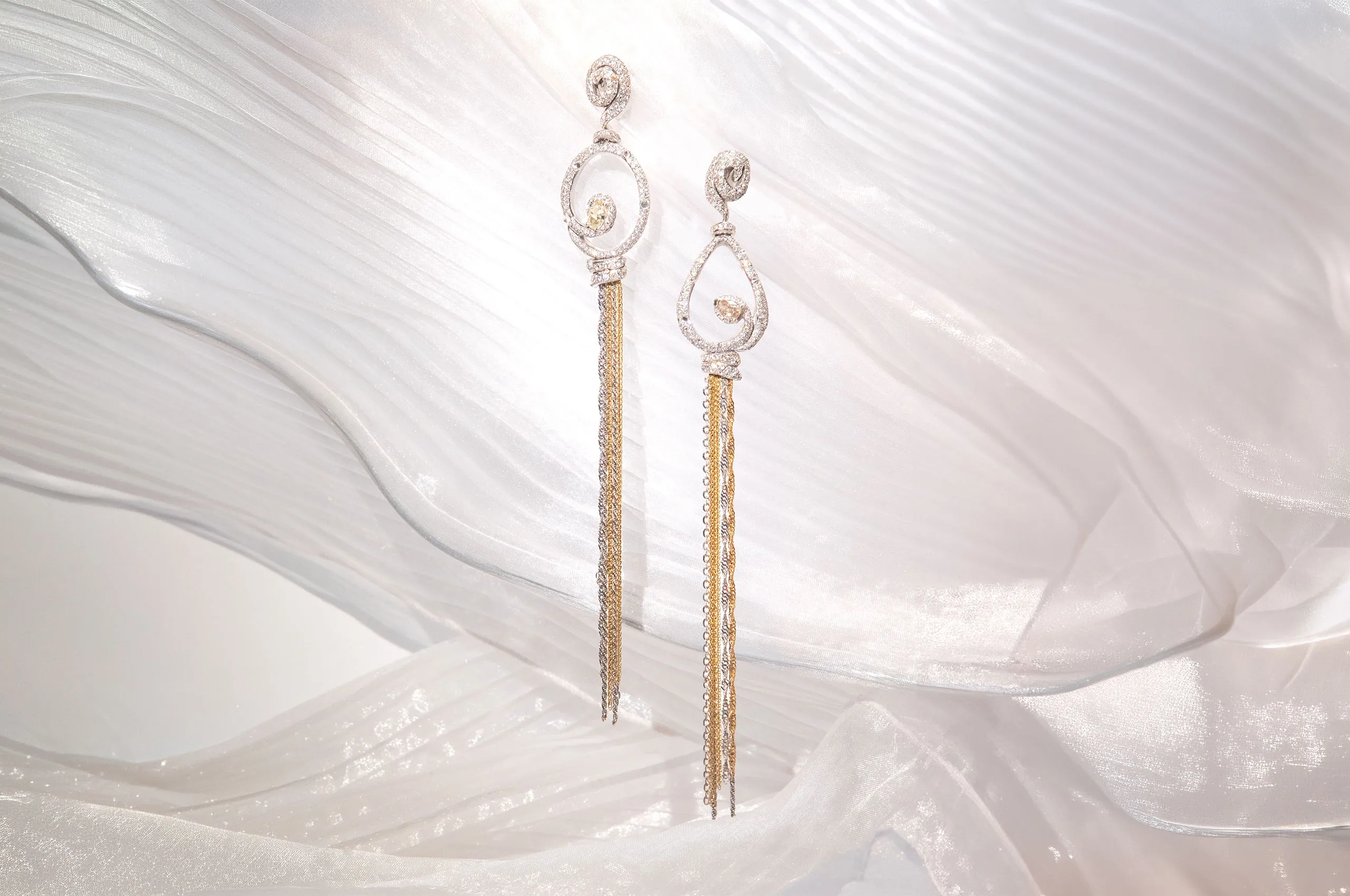 Long, asymmetric d'Avossa earrings in white and yellow gold, with white and fancy diamonds. The chains dance brightly to accompany every movement