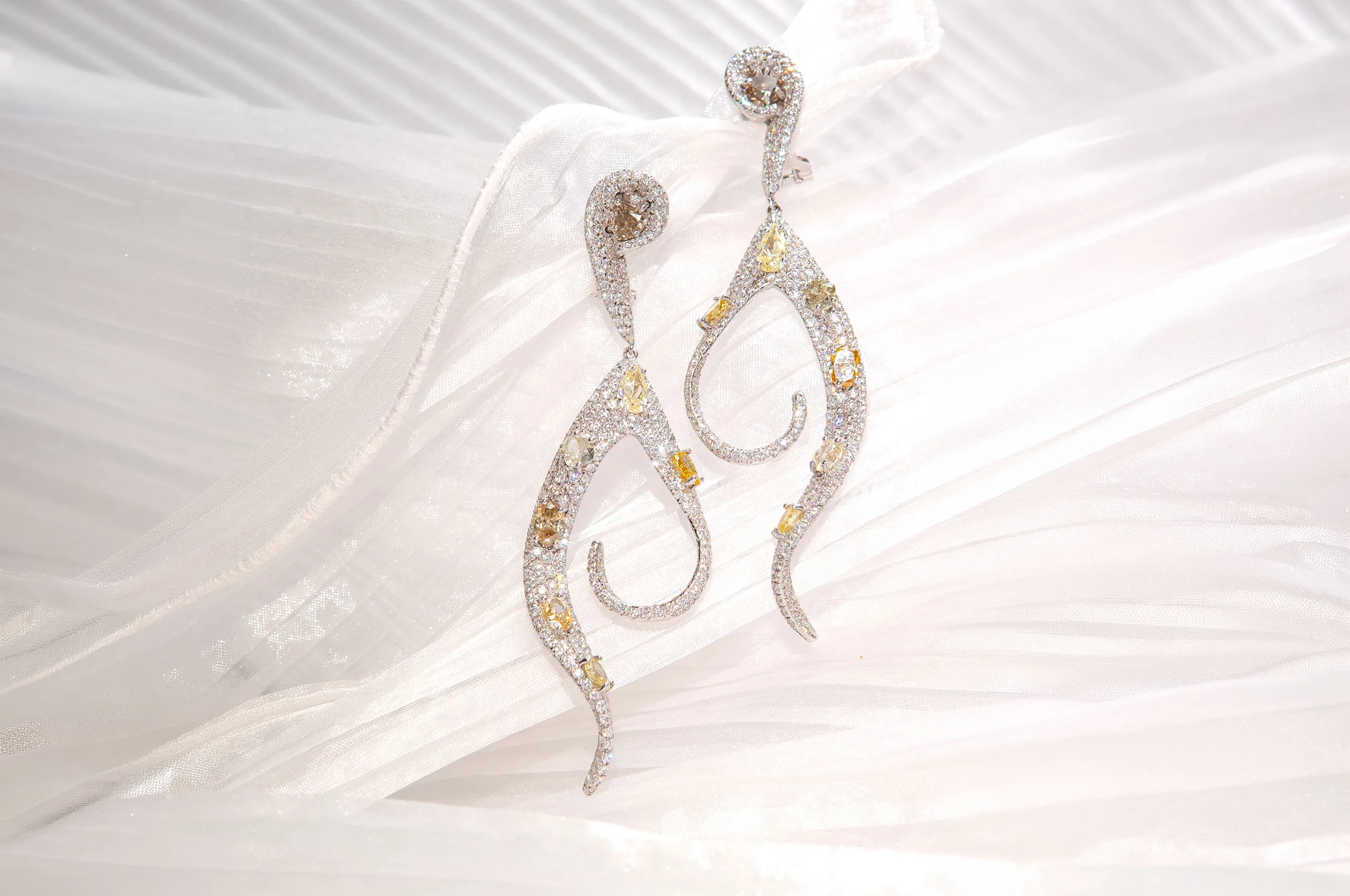 A pair of d'Avossa earrings that look like ribbons that unwind brightly, in white gold, white diamonds and natural fancy diamonds in various cuts and shades