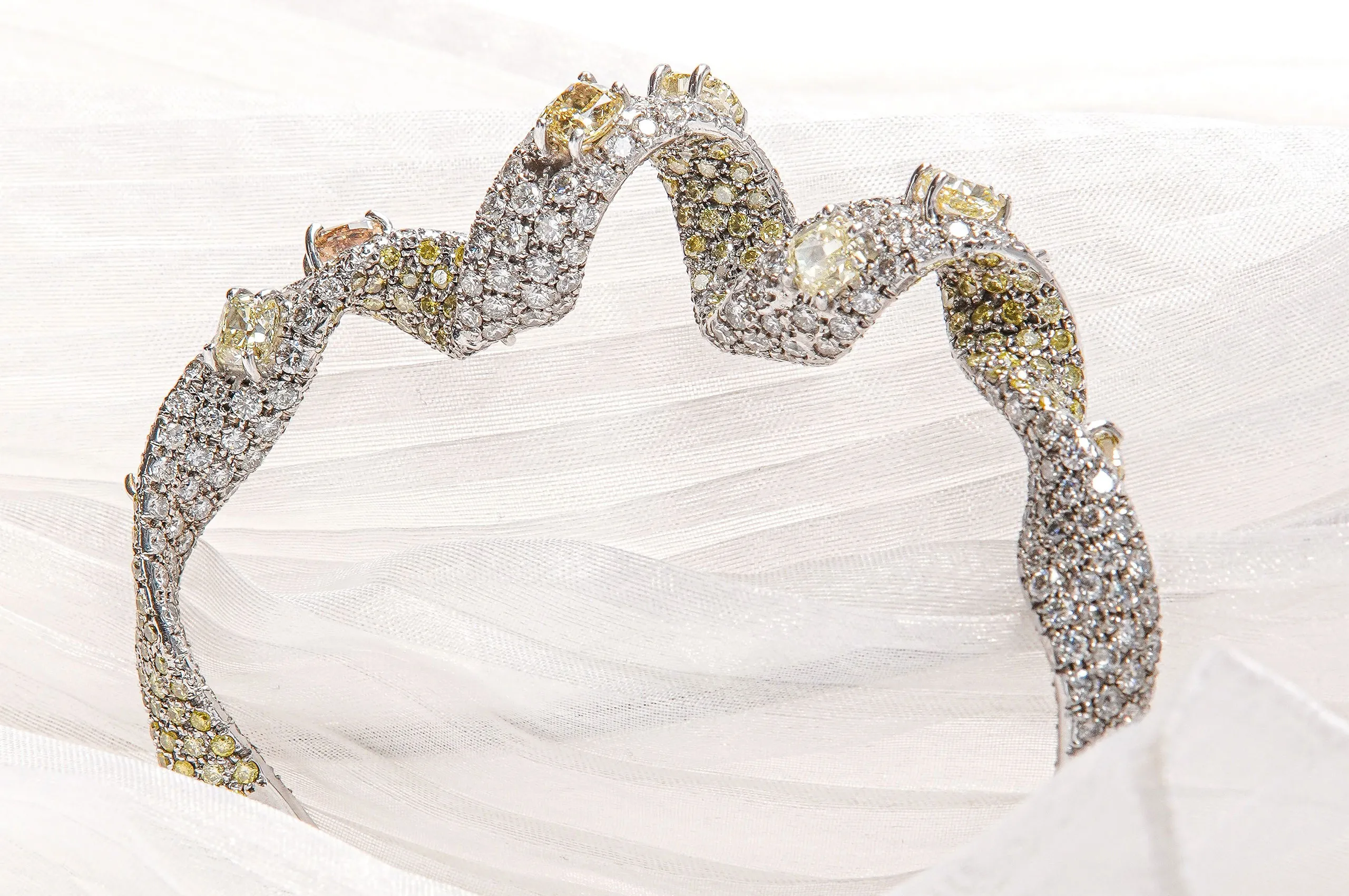 A ribbon unwinds softly to become an extraordinary white gold d'Avossa bracelet with pavé white diamonds and natural fancy diamonds in various shades