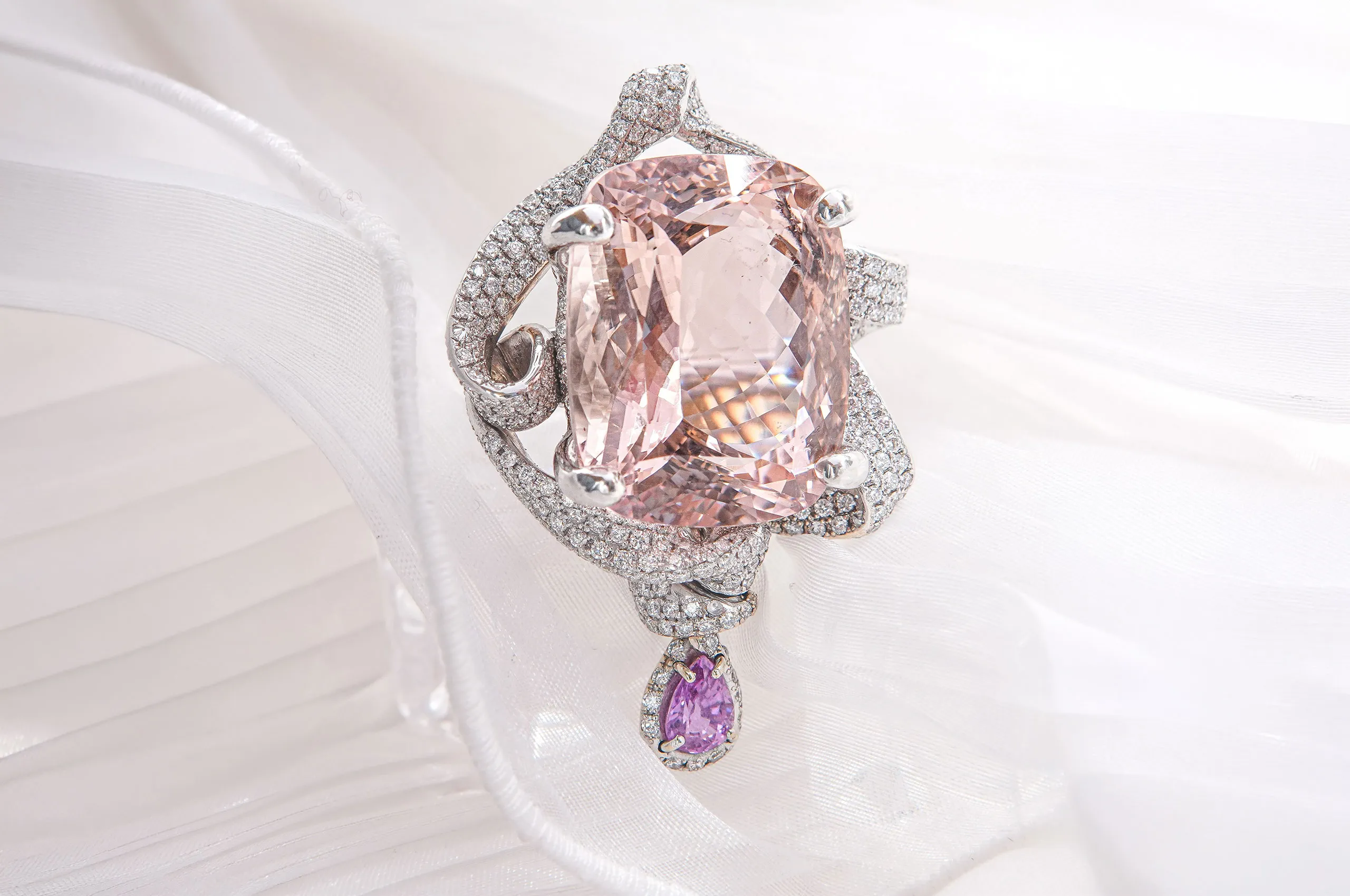 The star of this extraordinary d'Avossa ring is a large cushion-cut morganite wrapped in swirls of white gold and diamonds, with a teardrop-shaped pink sapphire beneath adding a touch of light movement