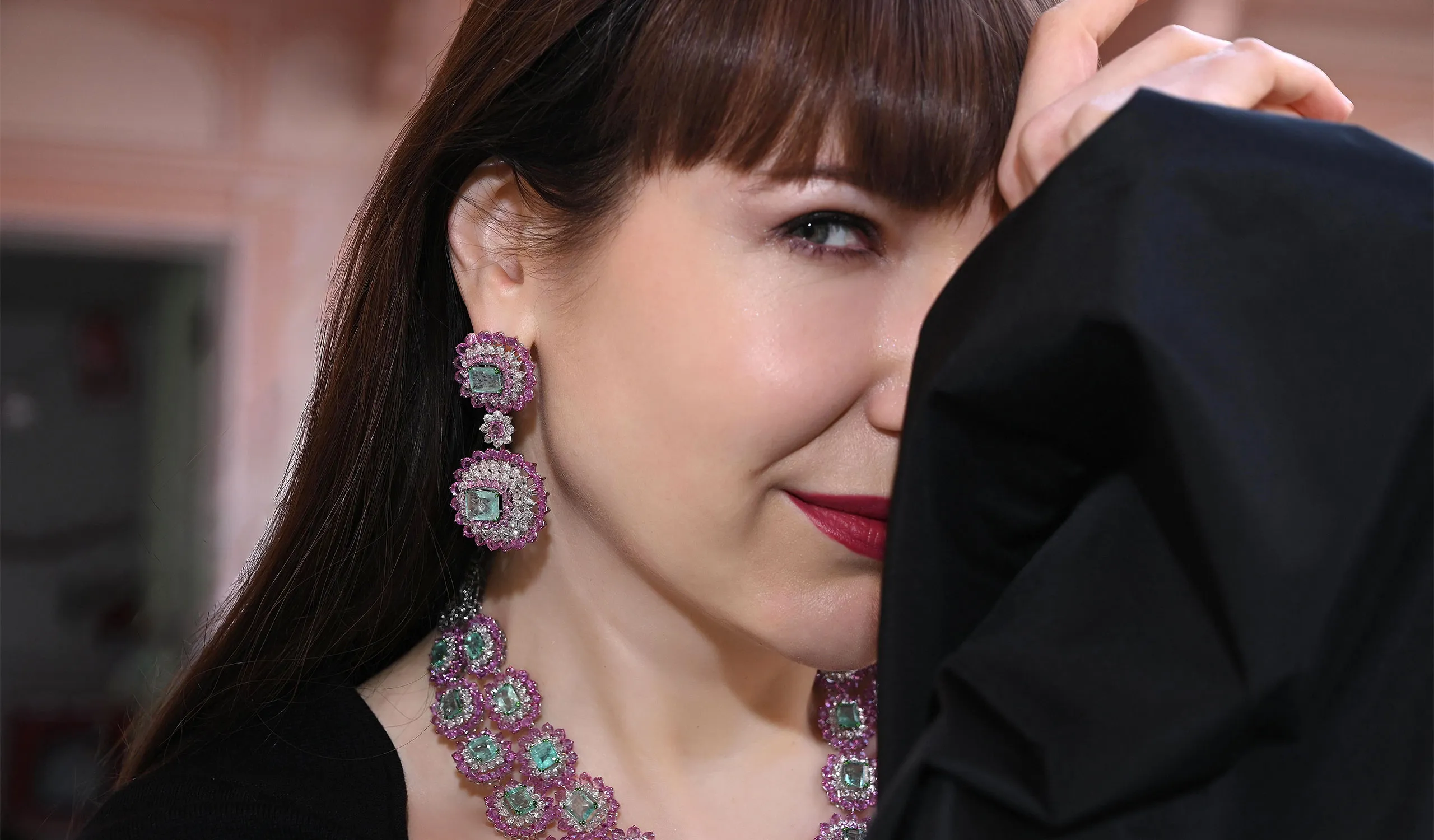 <p>Katerina Perez wears a matching necklace and earrings from the Diviano One Collection, set with old Russian emeralds, pink sapphires and diamonds </p>