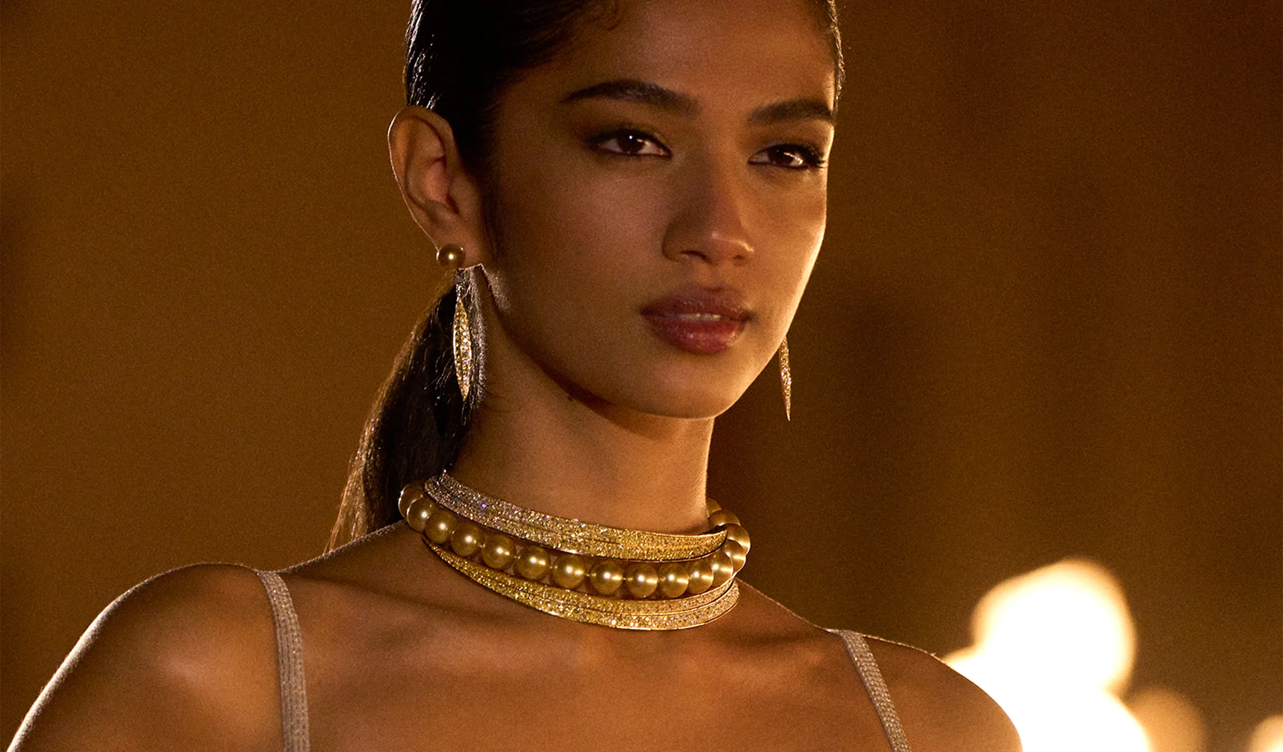 <p>The pearls are set between two contours of orangey-yellow and white diamonds</p>
