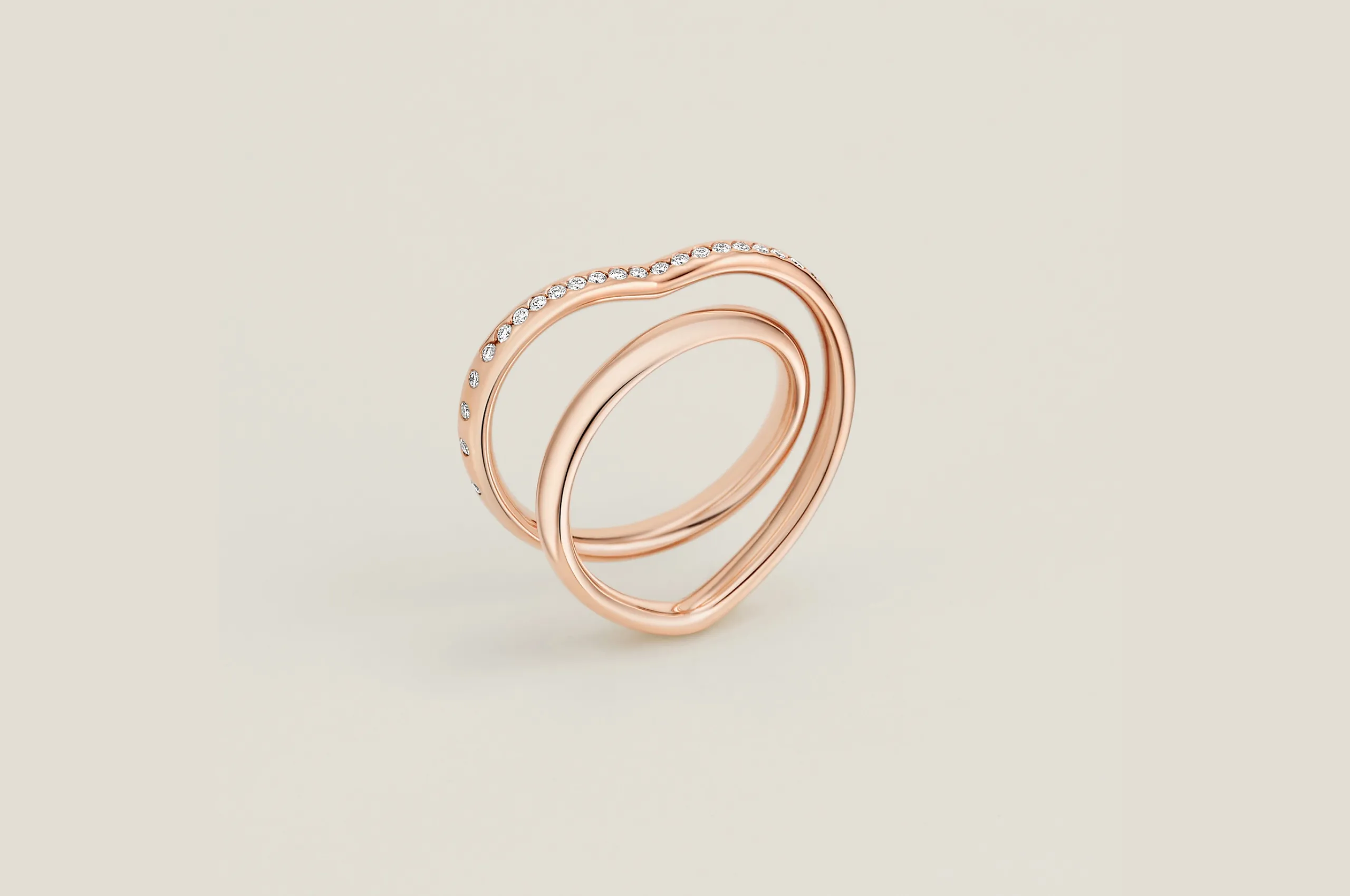<p>The Hermès Vertige Cœur ring in 18K rose gold with diamonds wraps around the finger to trace a heart shape.</p>