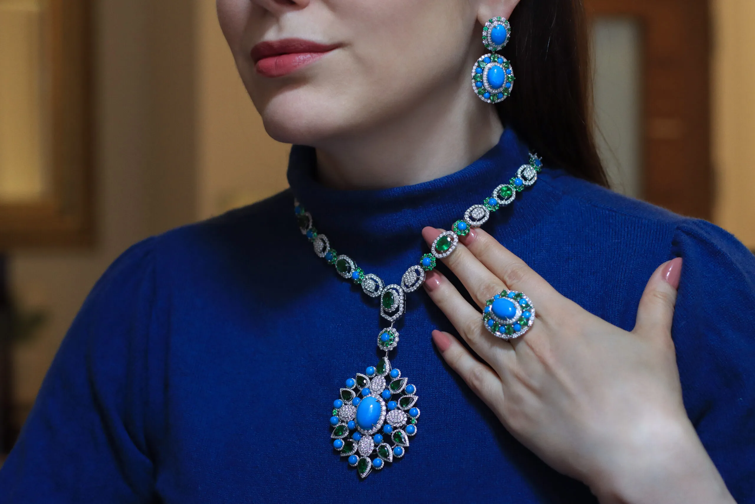 <p>Katerina Perez wears the AKANO Chikaodili suite comprising a necklace, ring and earrings set with round turquoise, tsavorite, and diamonds in 18k gold </p>