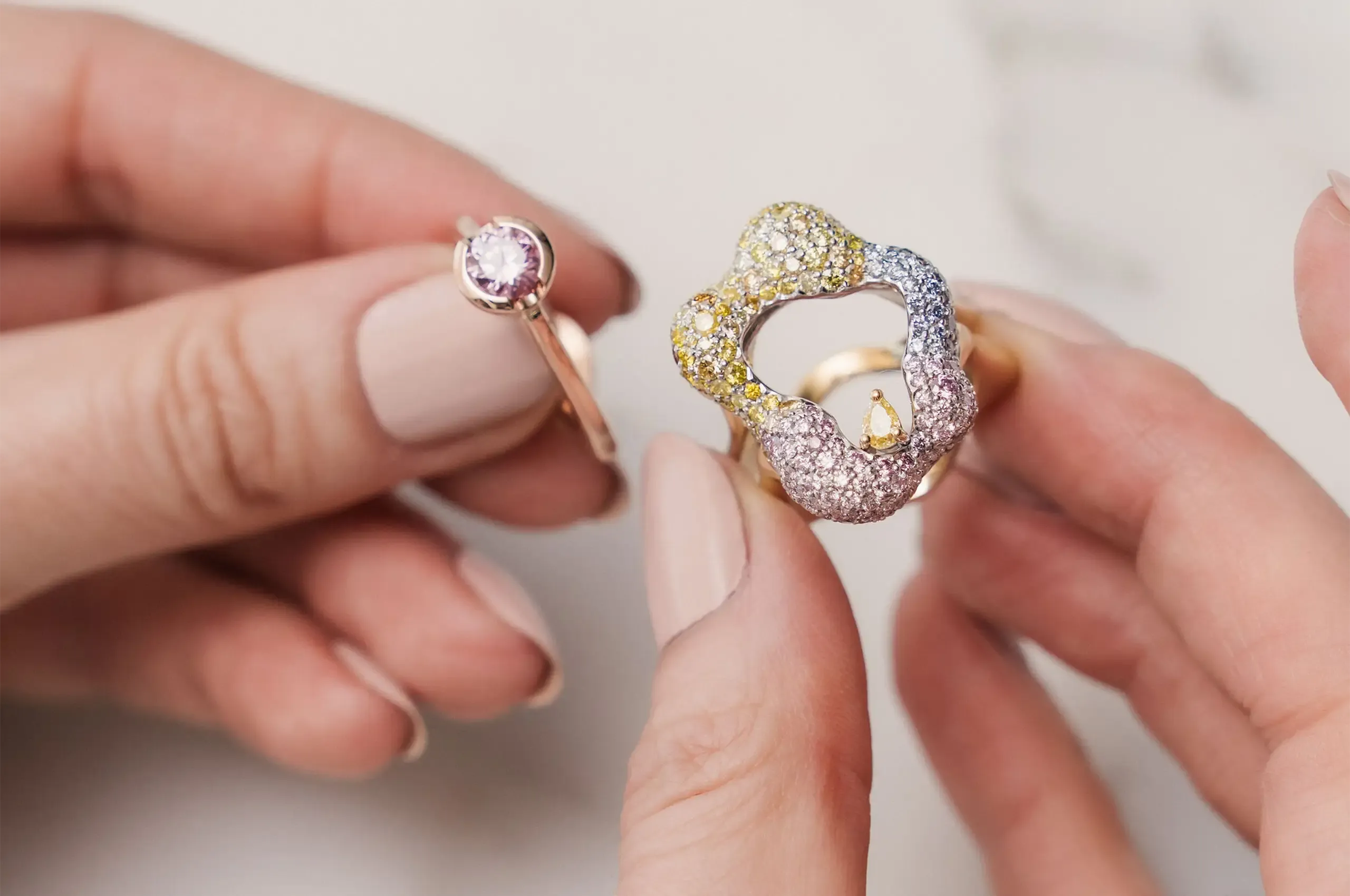 Entwined ring by Nazanin M. Khani of James Thredgold Jeweller, featuring an Argyle pink diamond framed by a removable jacket set with pink, yellow, orange and blue diamonds