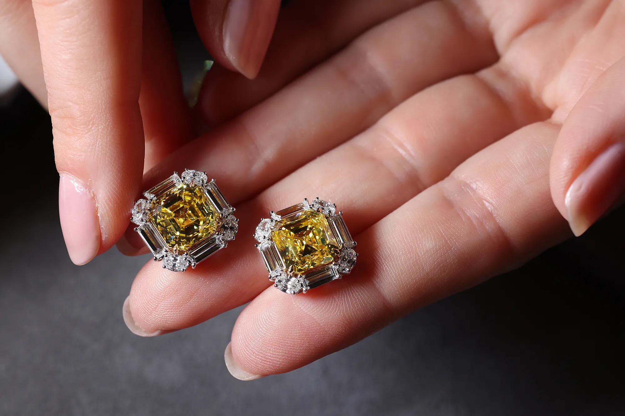 <p>Julius Klein earrings set with Vivid Yellow square emerald cut diamonds, framed by colourless baguette and oval cut diamonds</p>
