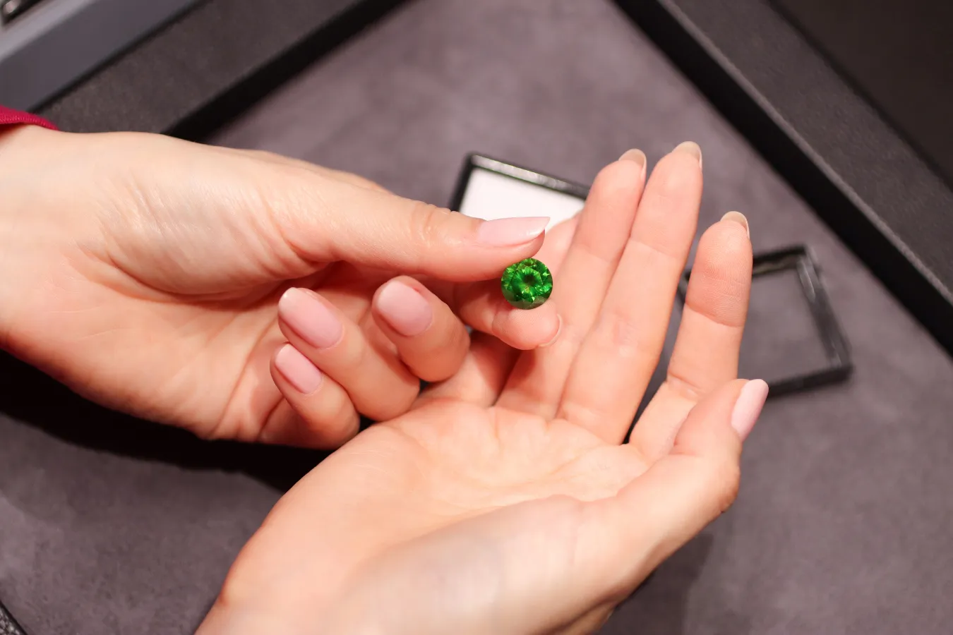 <p>Katerina Perez holds a round-cut Russian demantoid garnet supplied by Tsarina Jewels</p>