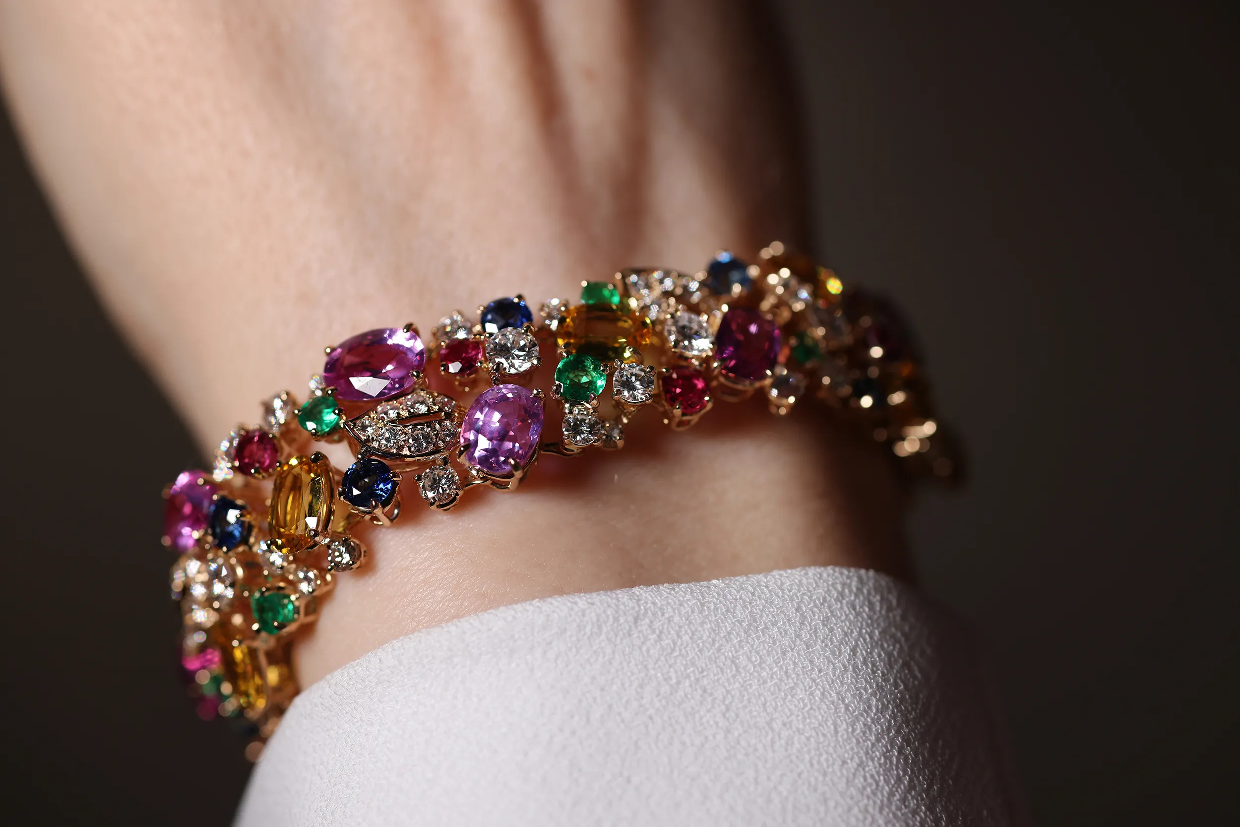 <p>An intricate mosaic of multi-coloured sapphires, rubies, emeralds and diamonds. A scatter bracelet like this can take up to six months to complete. The stone buying team collects the suite of stones, with a keen eye for balance in shape, size, cut, lustre and vibrancy. Then, the in-house lapidary matches table heights and crowns to ensure each stone is pristine</p>
