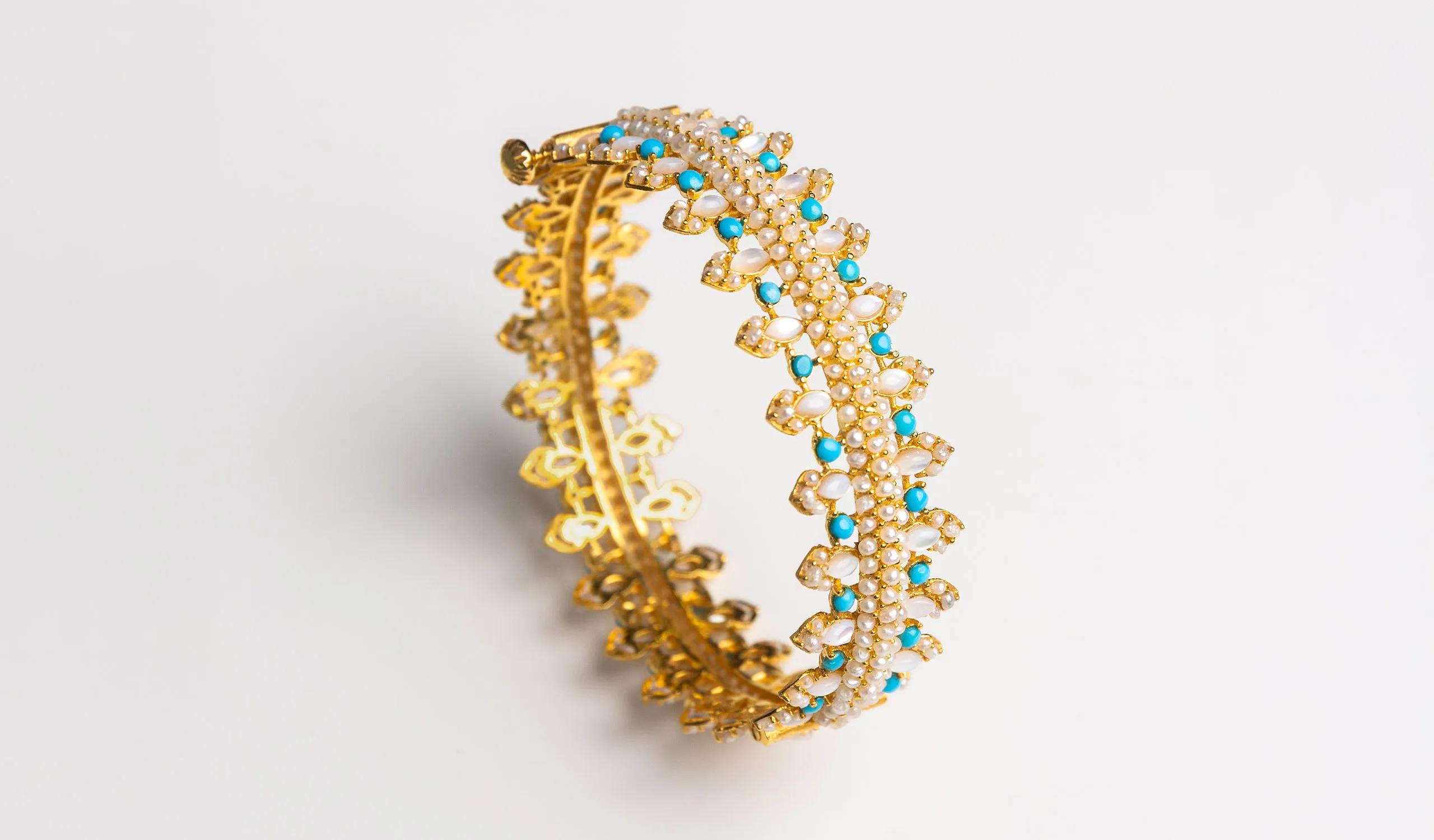<p>A Pearl Biography bangle in 21k yellow gold, set with natural Bahraini pearls, turquoise, mother-of-pearl and diamonds</p>
