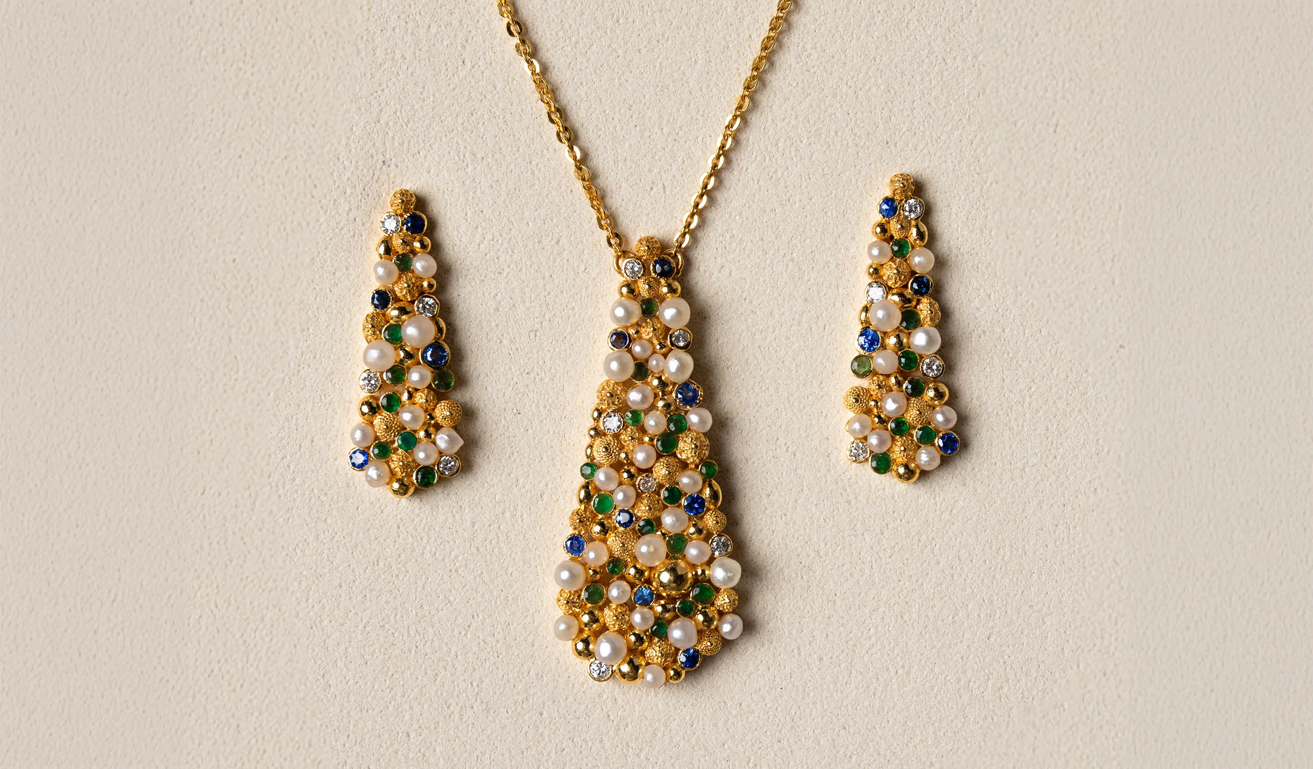 <p>A Pearl Biography pendant and earrings in 21k yellow gold, set with natural Bahraini pearls, sapphires, emeralds and diamonds</p>
