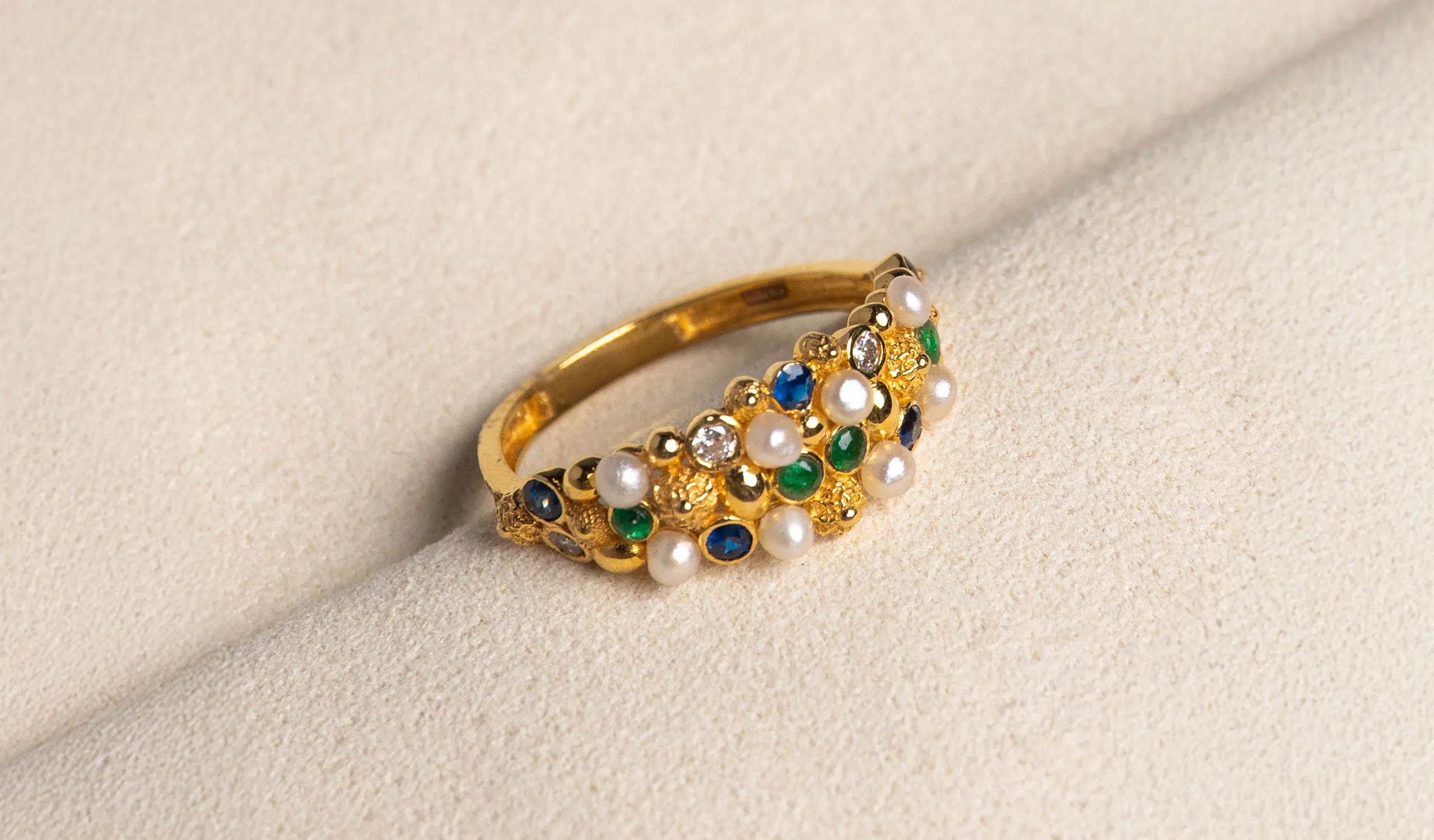 <p>A Pearl Biography ring in 21k yellow gold, set with natural Bahraini pearls, sapphires, emeralds and diamonds</p>

