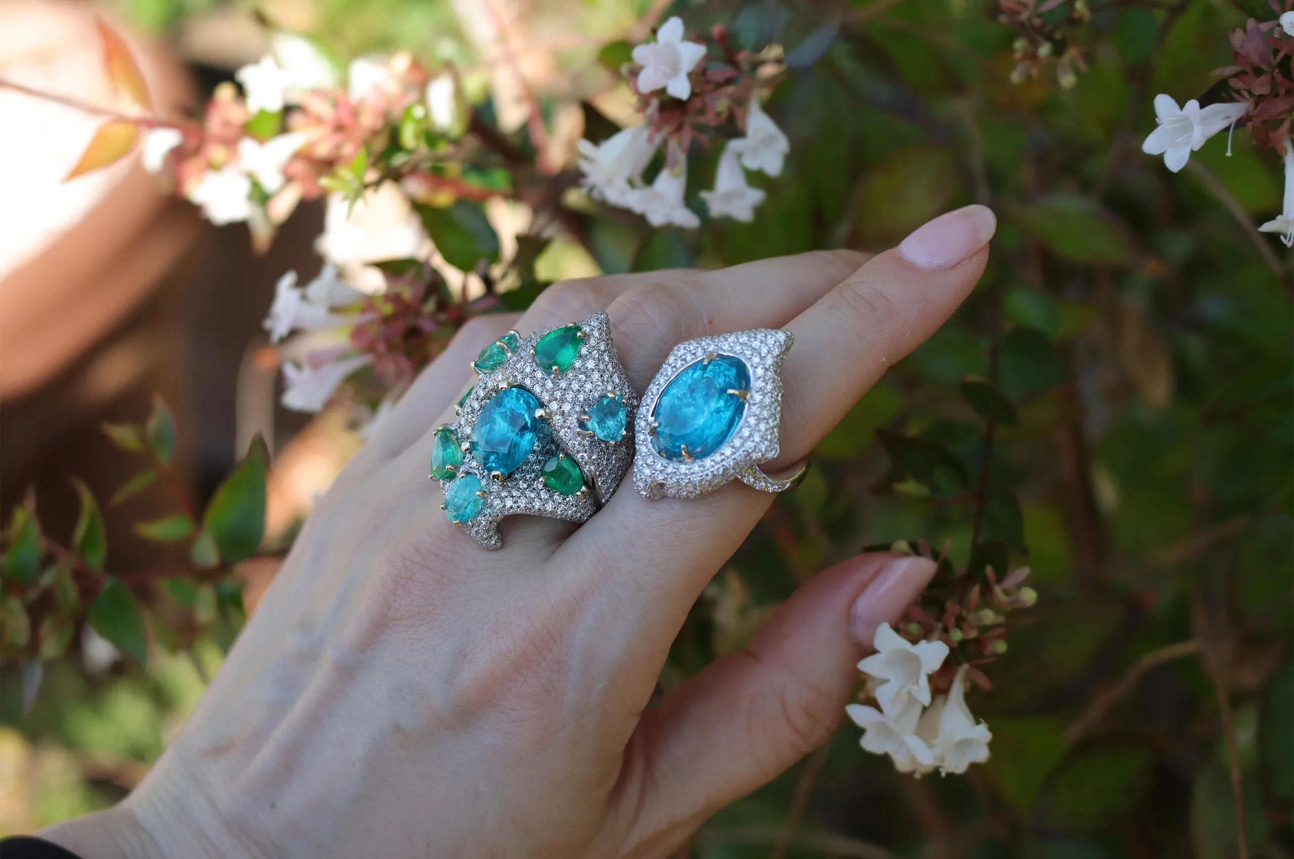 Recalling the hues of the sea, the ring on the left is set with a splendid apatite surrounded by emeralds, aquamarines and apatites, against a backdrop of pavé natural diamonds