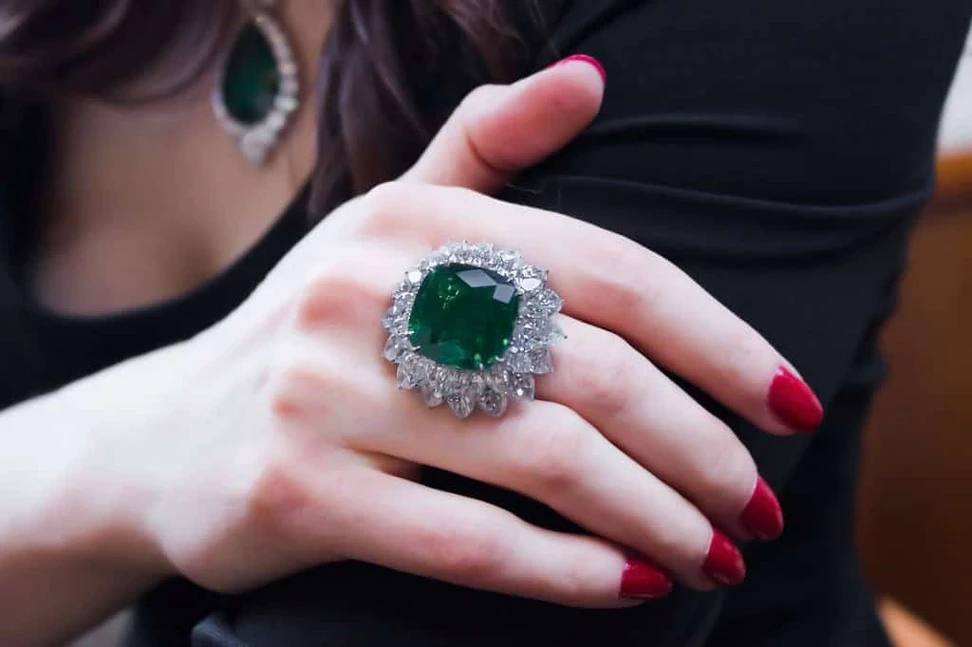 <p>A ring centered upon a gem quality 22cts cushion-cut Colombian emerald set within a double row of pear-shaped diamonds</p>