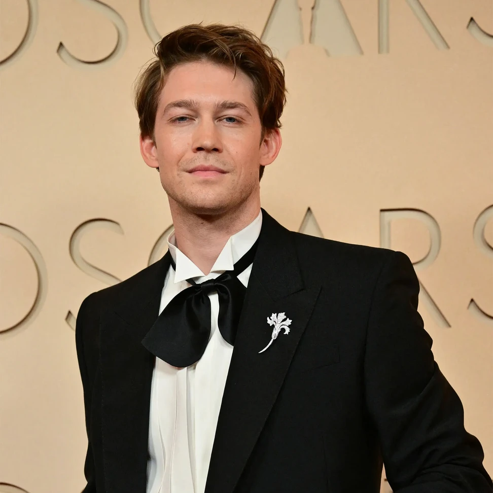 <p>Joe Alwyn wears Chaumet <i>Œillet brooch</i> in white gold, set with brilliant-cut diamonds</p>
