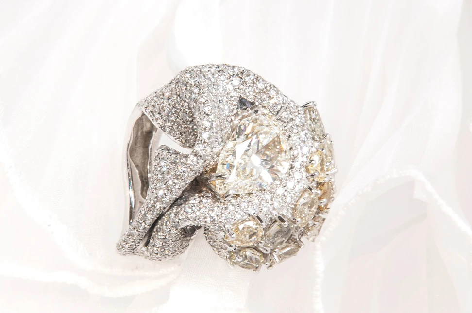 A Maison d'Avossa ring with a dense pavé of white diamonds, between whose folds a fancy drop diamond stands out, accompanied by other smaller fancy diamonds in different shades of natural yellow