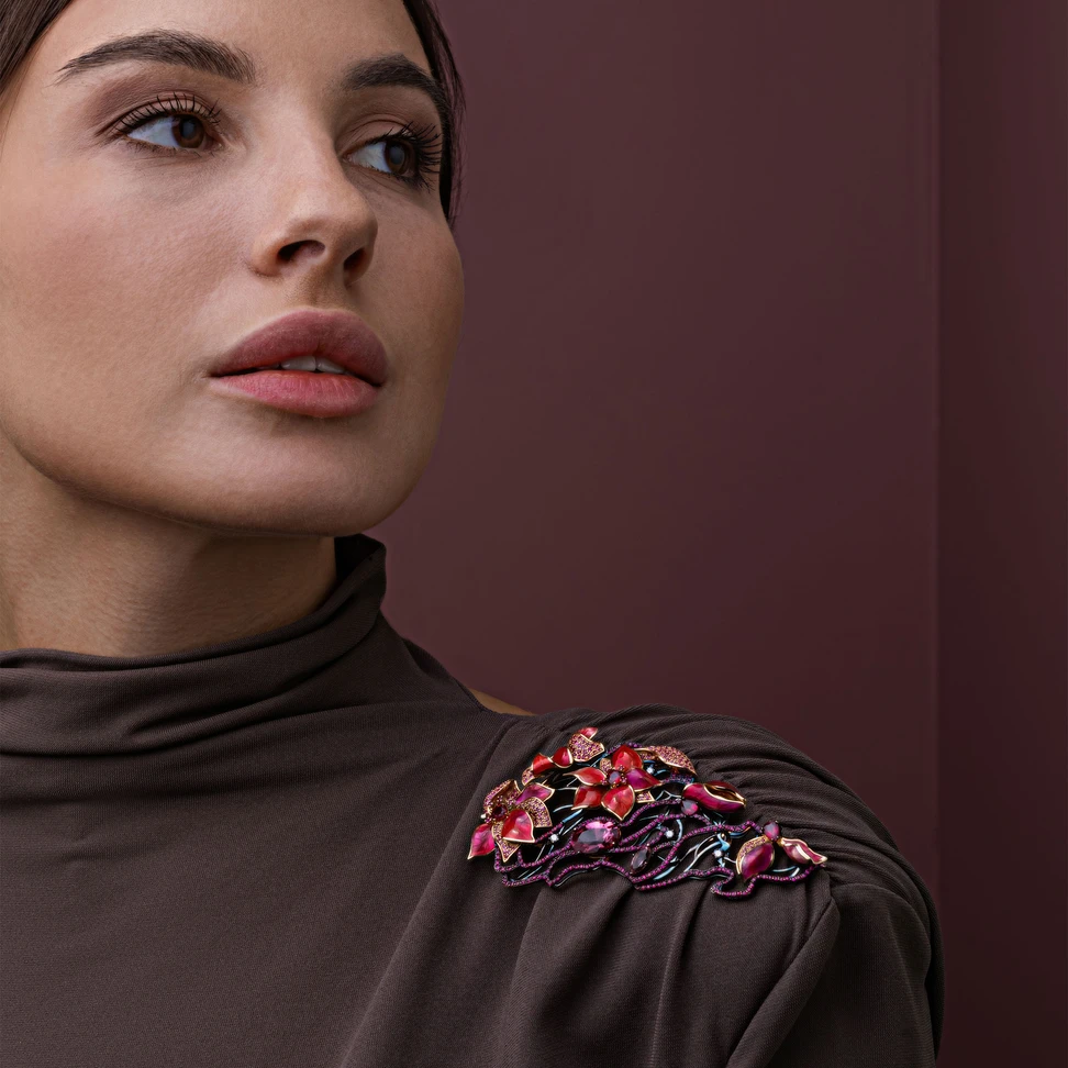<p>A model wears the IDORO Sakura – Wind in the Garden brooch in blackened 18k rose gold set with a 4.31 carat pink spinel from the Pamir Mountains, surrounded by round and pear-shaped Burmese rubies, ruby pavé, pink sapphires, morganite and diamonds</p>

