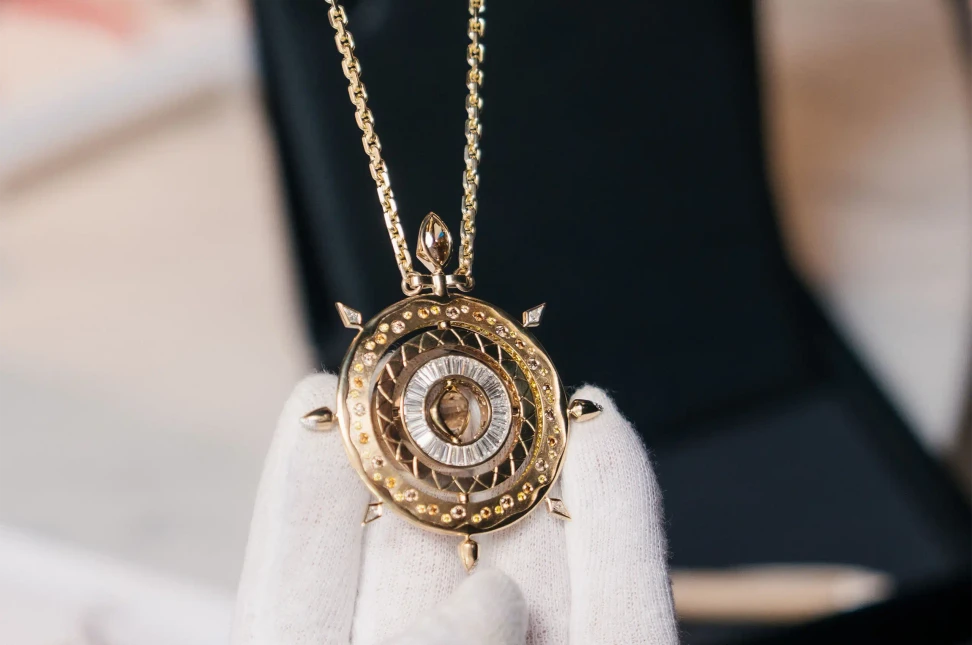 The Origins necklace by Nadia Neuman of Mondial featuring a rough champagne diamond set in 18ct yellow gold, surrounded by rotating rings set with white and coloured diamonds