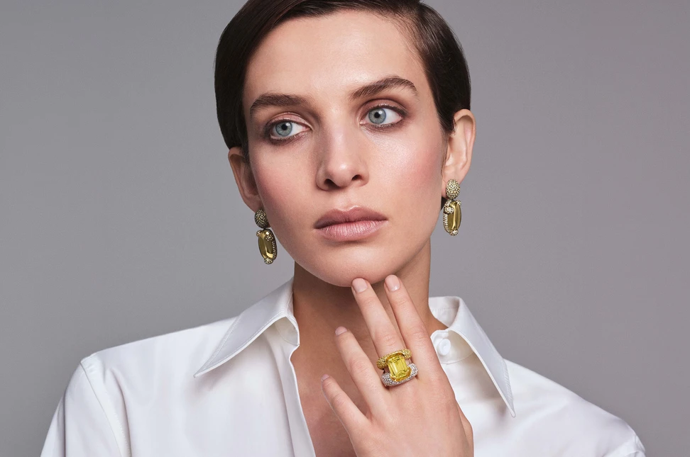 A model wears Pomellato Stile Libero Ray of Light ring in yellow gold with 1 octagonal-cut yellow sapphire, 206 yellow sapphires and 244 diamonds and Marvelous Griffe earrings in rose gold with 2 oval cabochon-cut heliodors and 572 yellow sapphires