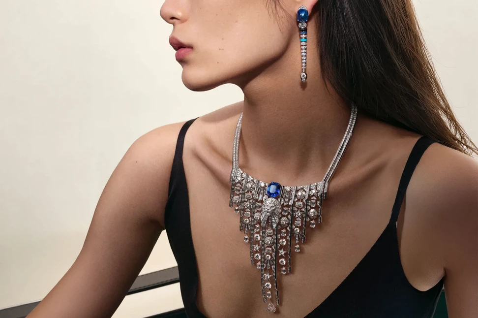 A model wears Chanel Imprimé Lion necklace in white gold and rose gold, set with diamonds and sapphire and Symbole Saphir earrings in white gold, set with diamonds, sapphires, turquoise and onyx

