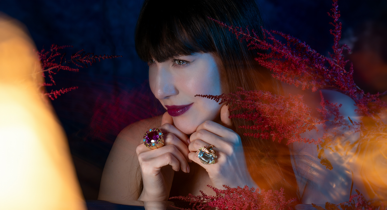 Katerina Perez wears cocktail rings by Garnazelle Joaillerie, including (left) the Ciel Poétique ring with a 39.42-carat cushion-shaped amethyst, turquoise, and further amethysts set in 18k recycled yellow gold 