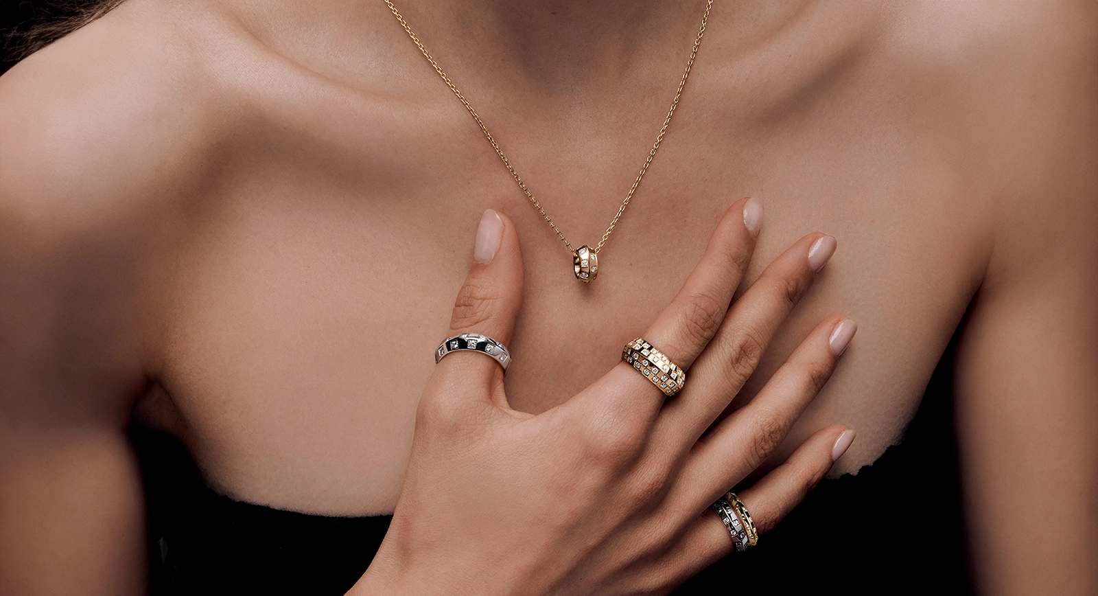 1  Model wearing Louis Vuitton Le Damier round pendant, studded with diamonds on a yellow gold chain, paired with a two-row diamond ring in white gold and a four-row diamond ring in yellow gold, featuring the signature chequerboard pattern