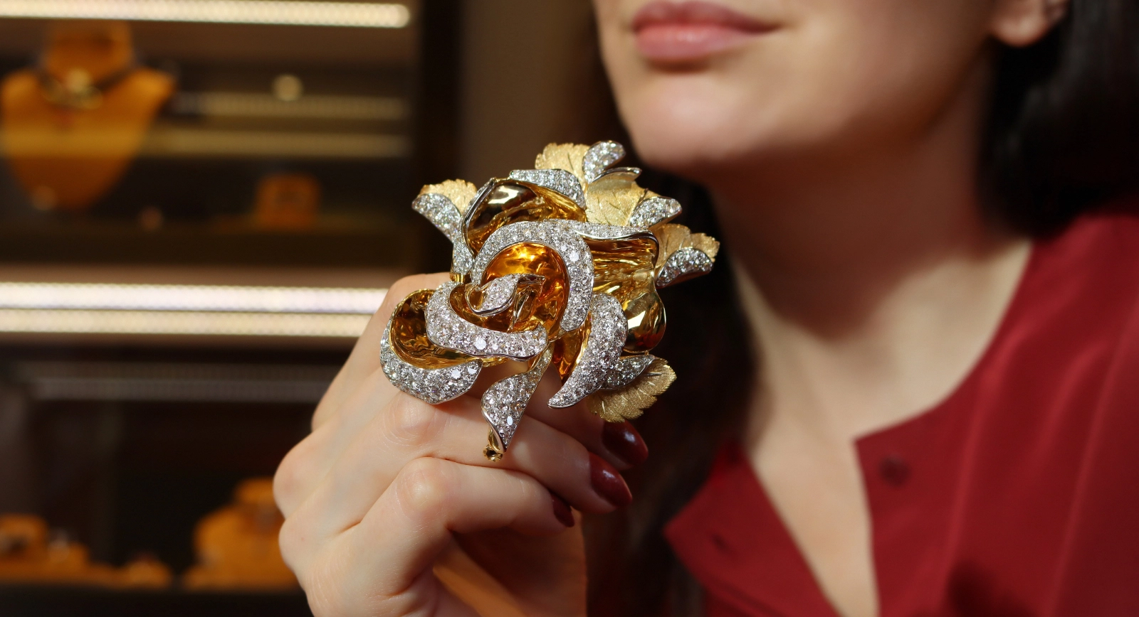 Katerina Perez holding the Fratelli Piccini Rosae brooch featuring 16.53 carats of diamonds showing the arrangement of the petals in 18k yellow gold