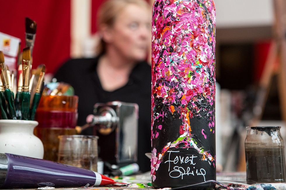 One of the bottles painted by Liesbeth Swinnen with the artist herself on the background