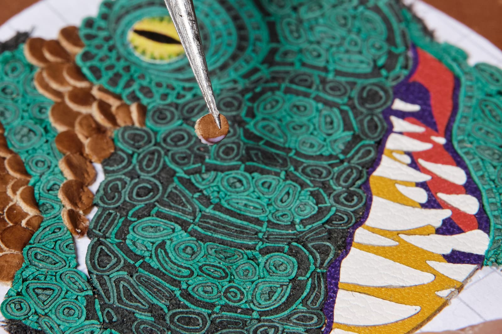 The dinosaur's gnarly scales and razor-sharp teeth have been “painted” in leather mosaic and leather marquetry