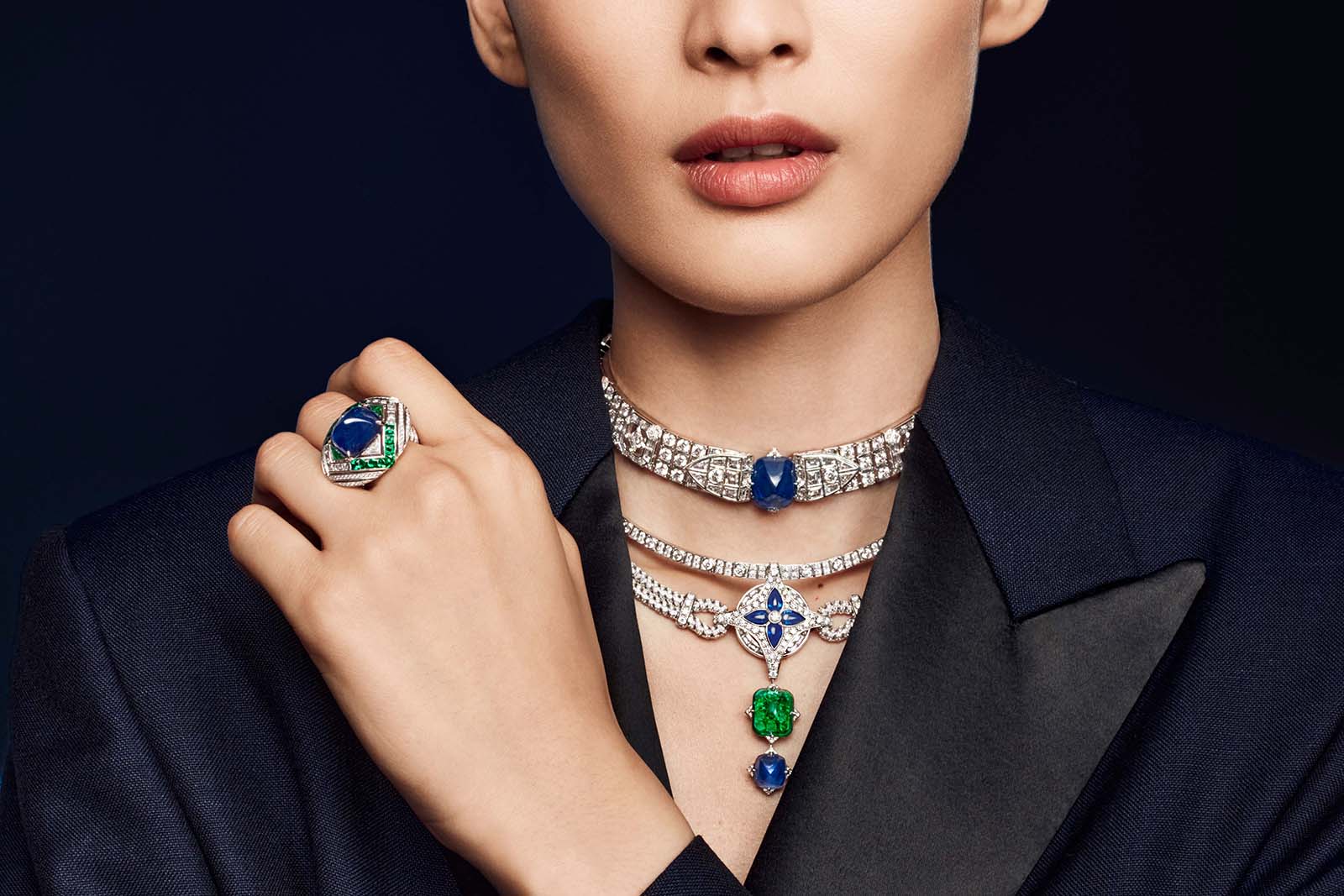 A model wears the Le Mythe necklace and the Le Mythe ring from the Bravery by Louis Vuitton Collection with sugar-loaf sapphires and emeralds, and LV Monogram star-cut diamonds